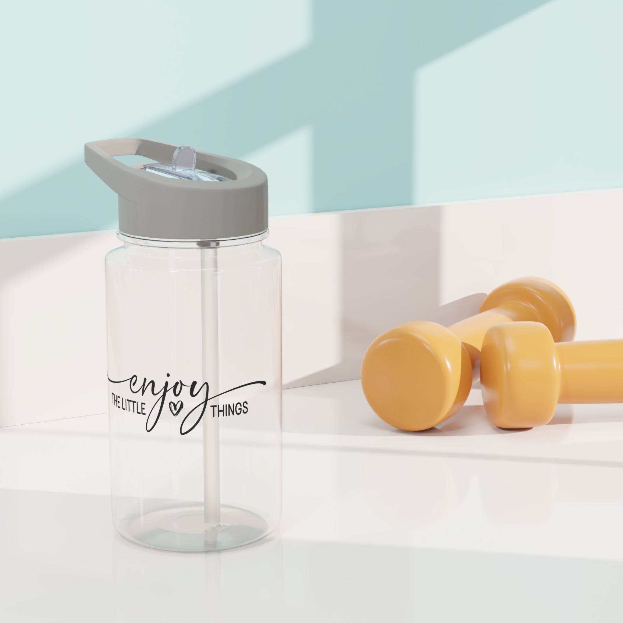 Clear BPA-free Tritan bottle with gray lid and enjoy the little things design next to yellow dumbbells