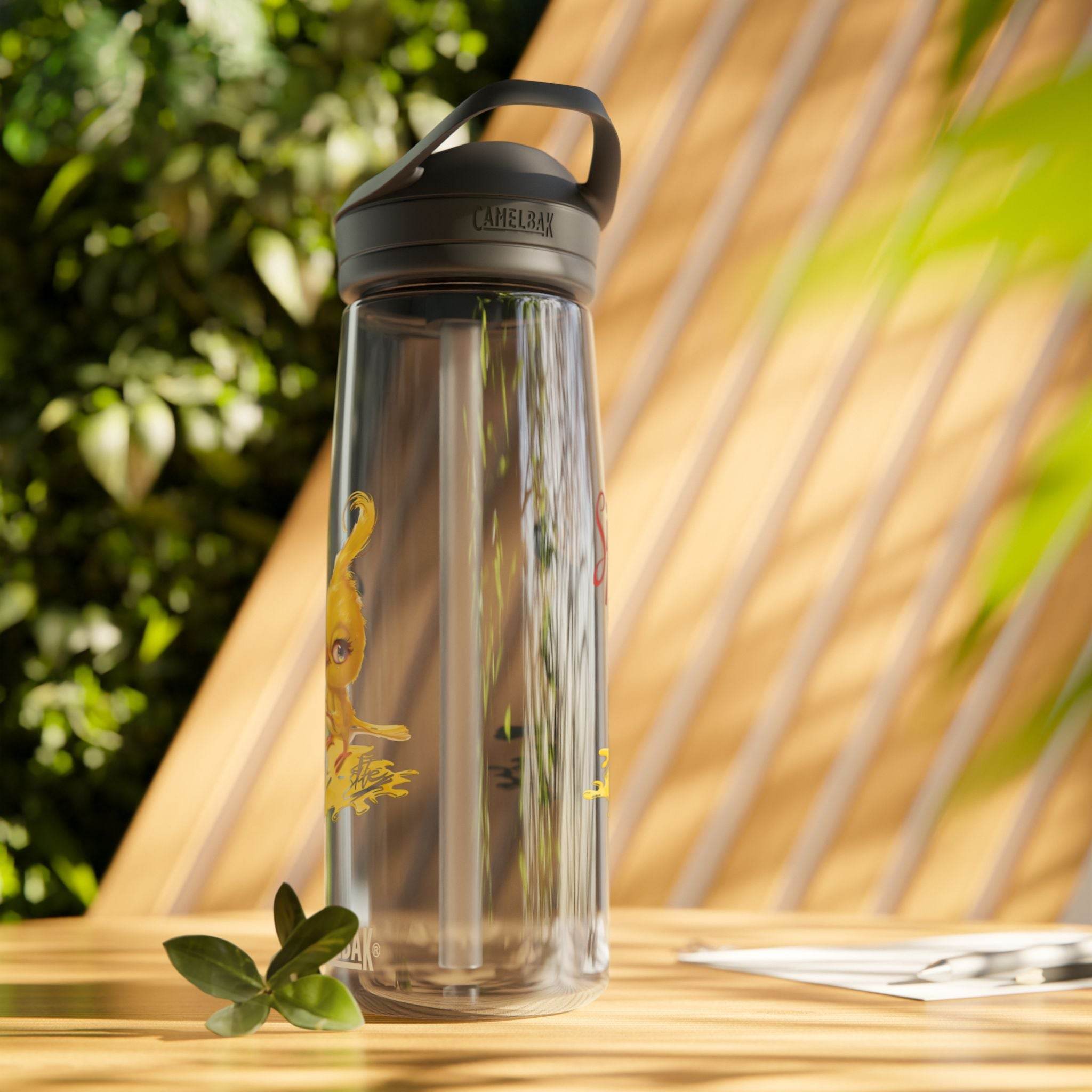 Clear Camelbak eco-friendly water bottle with black lid placed on wooden surface with green foliage background