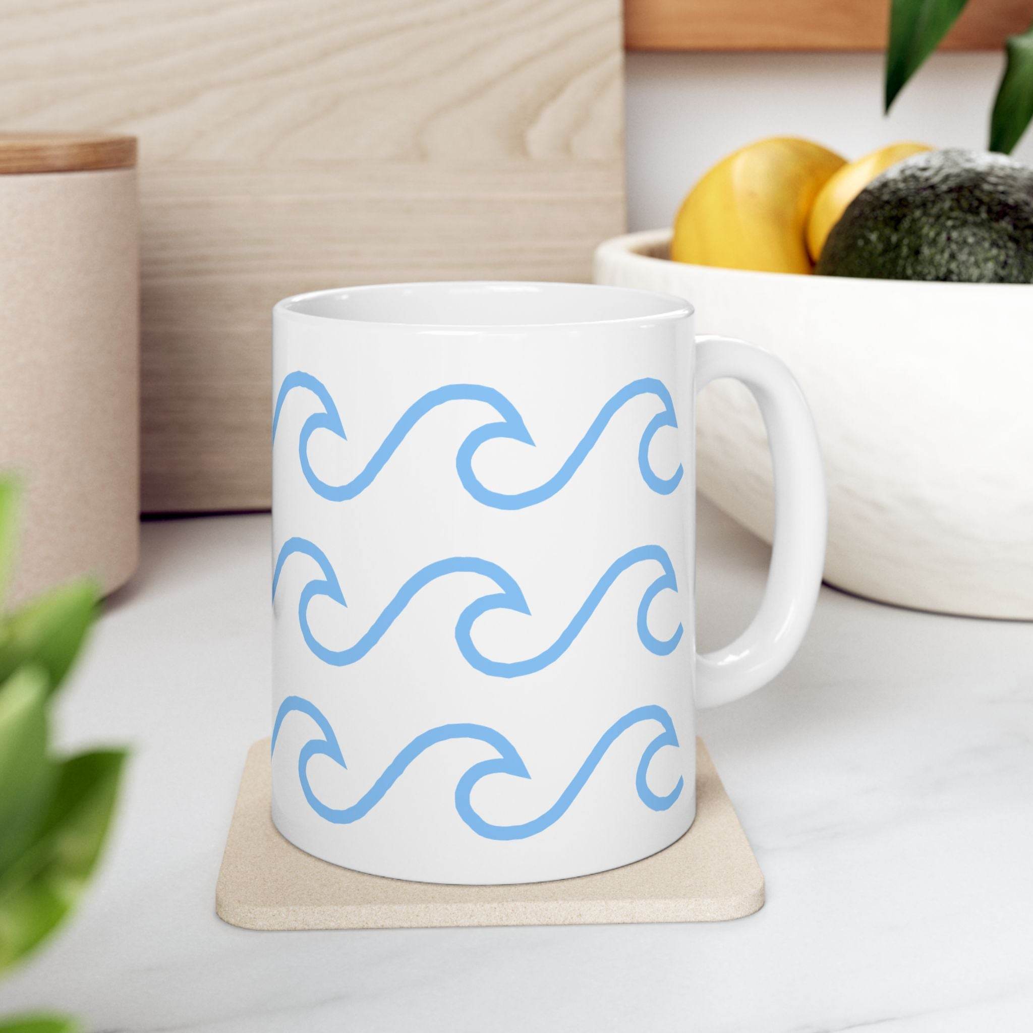 White ceramic mug with wave pattern in light blue on a coaster on kitchen counter
