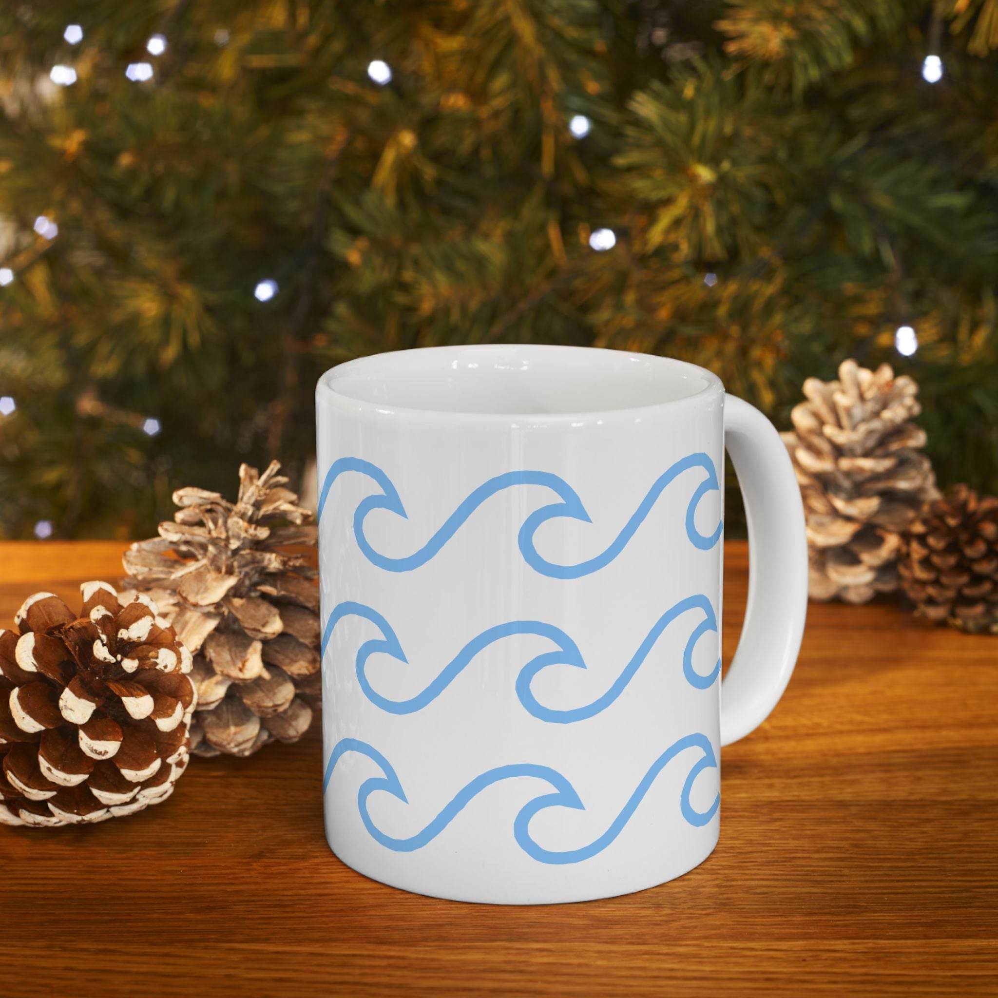 Printify white ceramic mug with wave pattern in blue on wooden table with pinecones and festive background