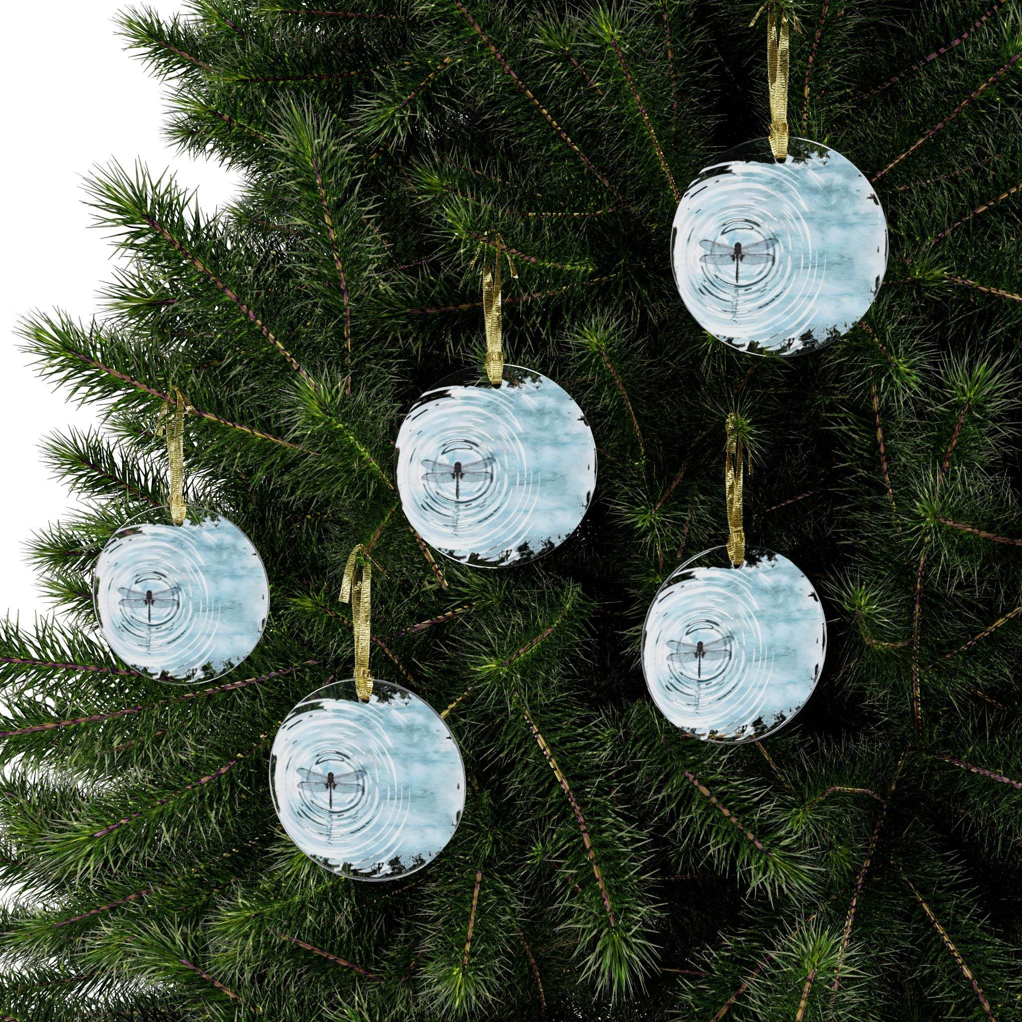 Printify dragonfly christmas ornament hanging on green pine tree branches with rippled water design