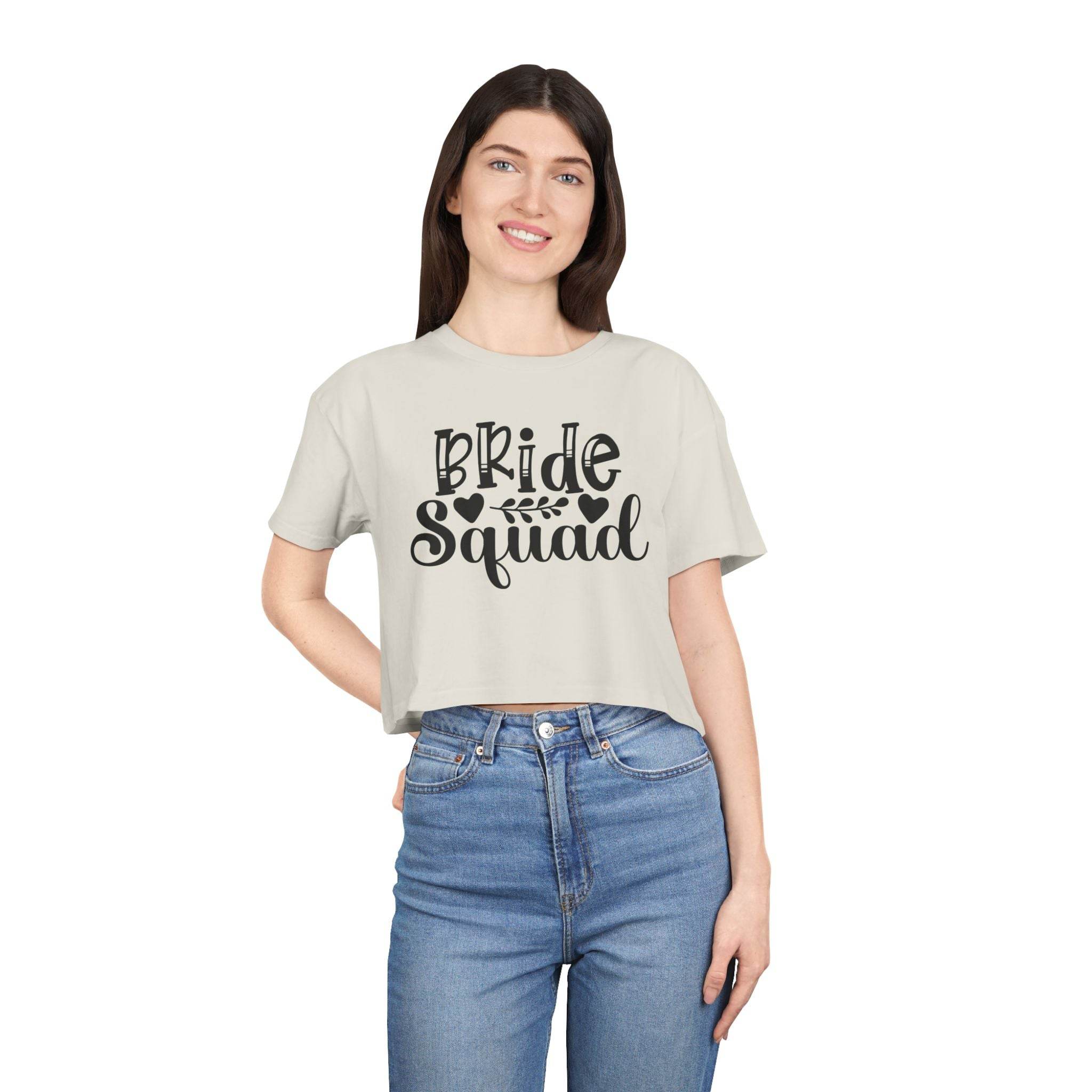 Smiling woman modeling eco-friendly bride squad crop top by Printify light beige cropped tee with black script