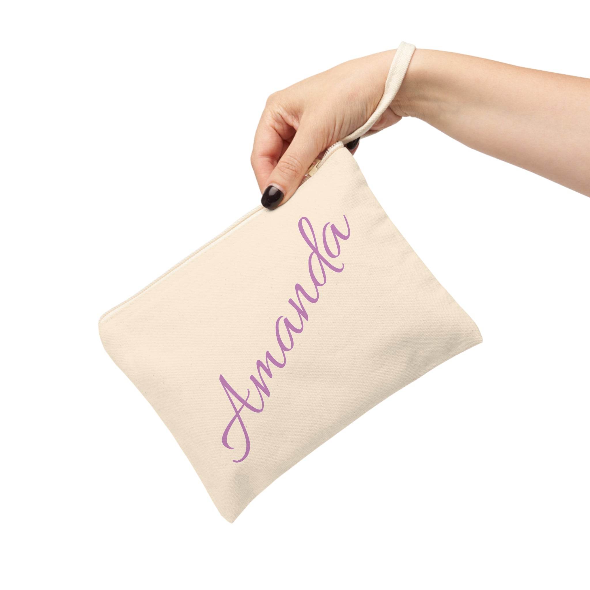 Hand holding Printify personalized eco-friendly zipper pouch in natural canvas with purple Amanda script and wrist strap