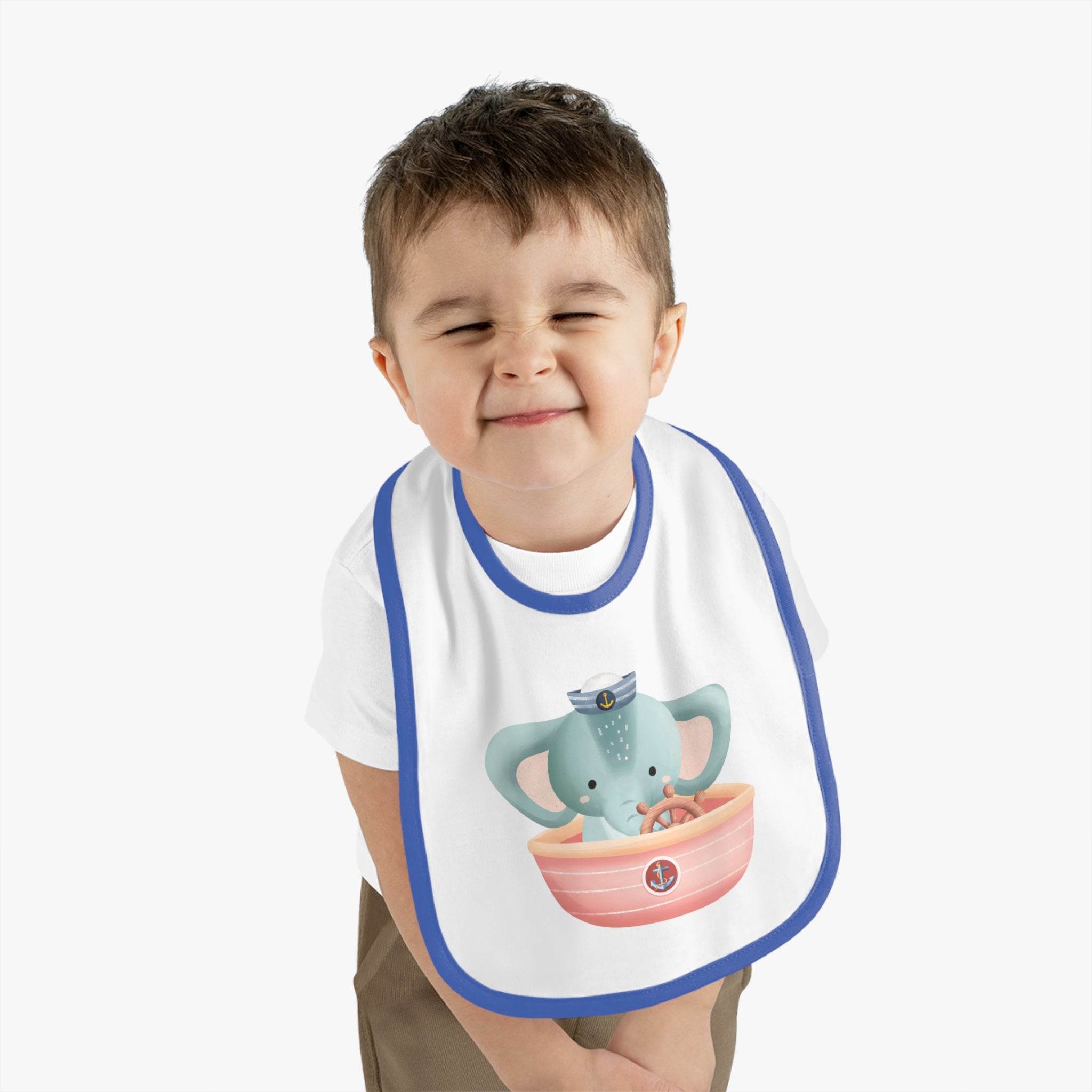 Toddler wearing eco-friendly baby bib with blue trim and cute elephant design boating in a pink boat