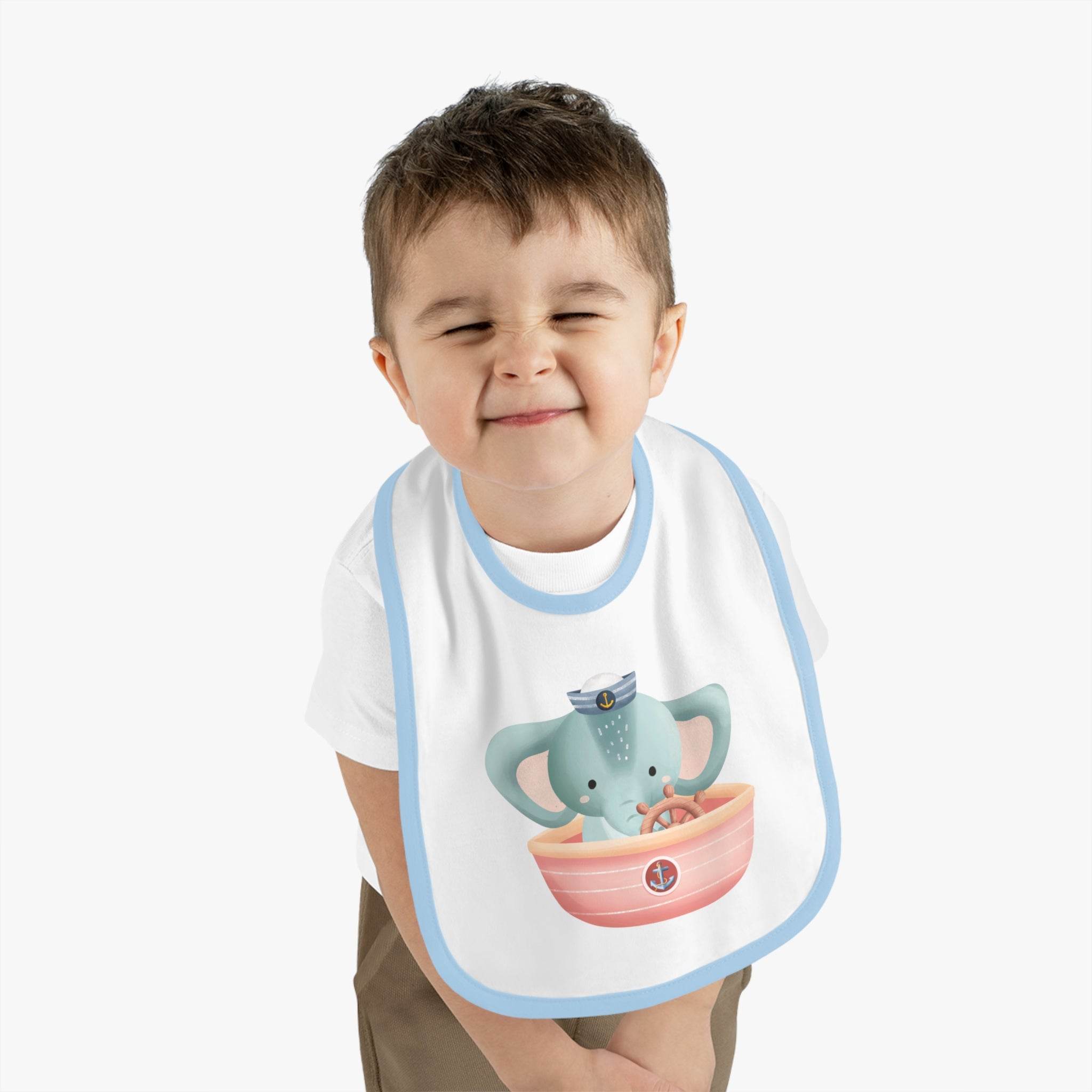 Toddler wearing Printify eco-friendly baby bib with blue trim and playful elephant sailor design