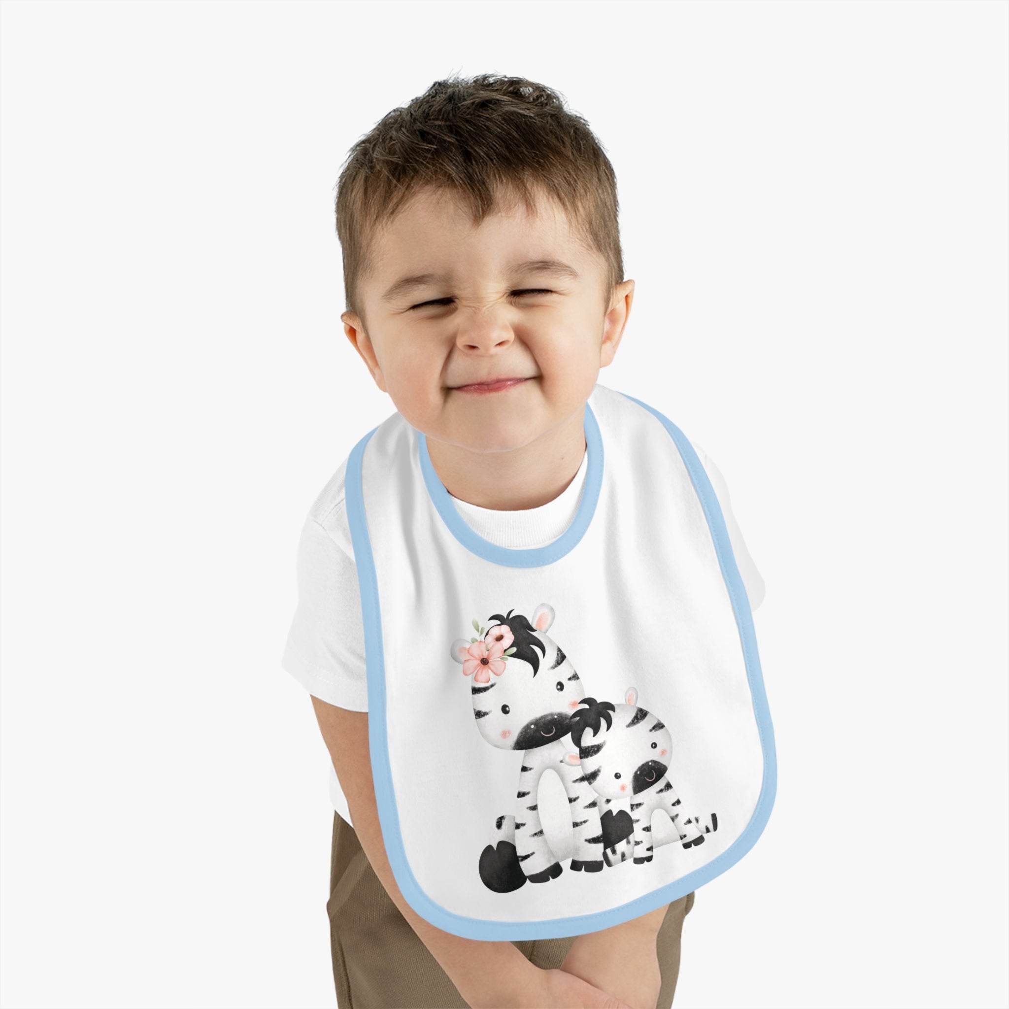 Toddler wearing an eco-friendly baby bib with a cute zebra design and blue trim