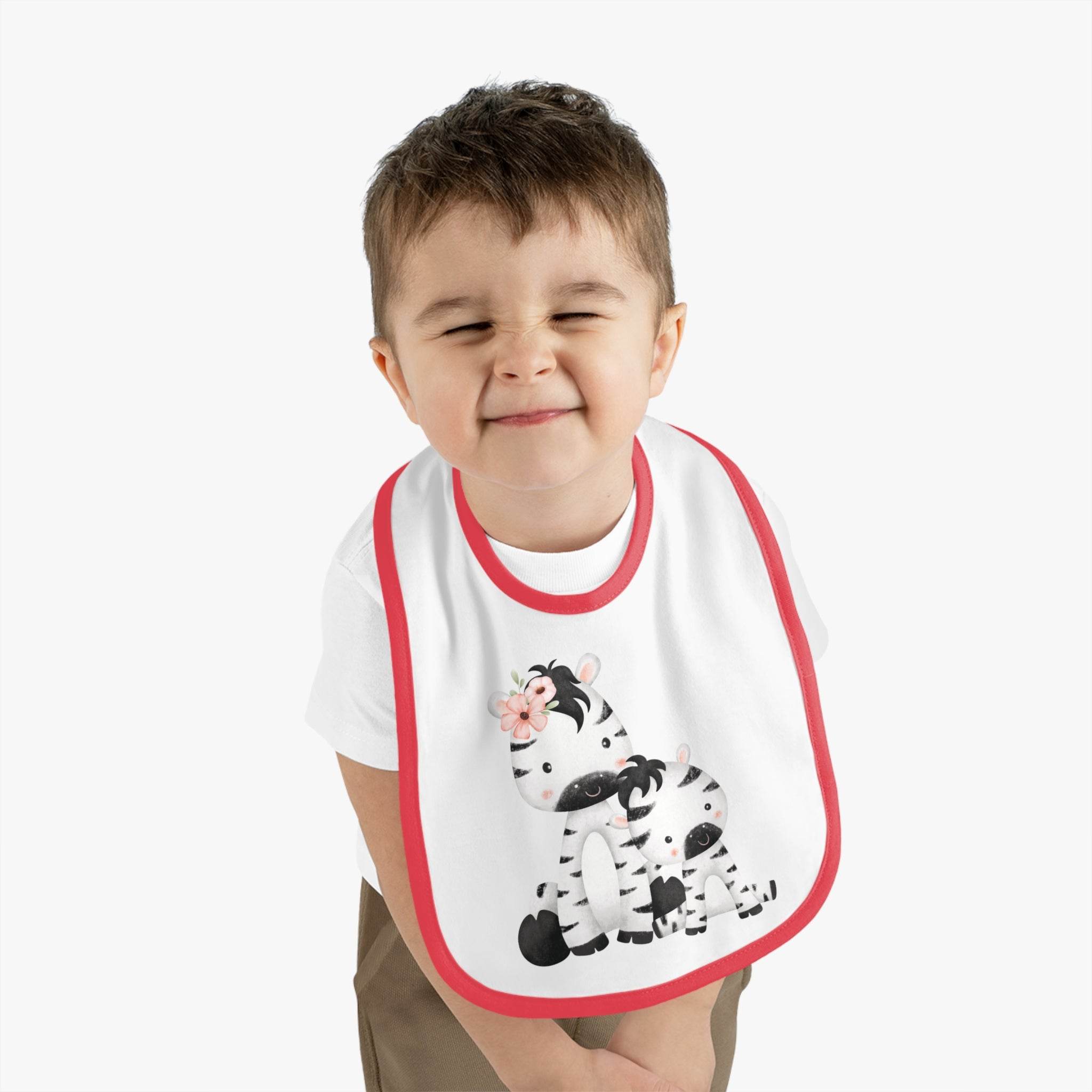 Toddler wearing a Printify eco-friendly baby bib with red trim and cute zebra design