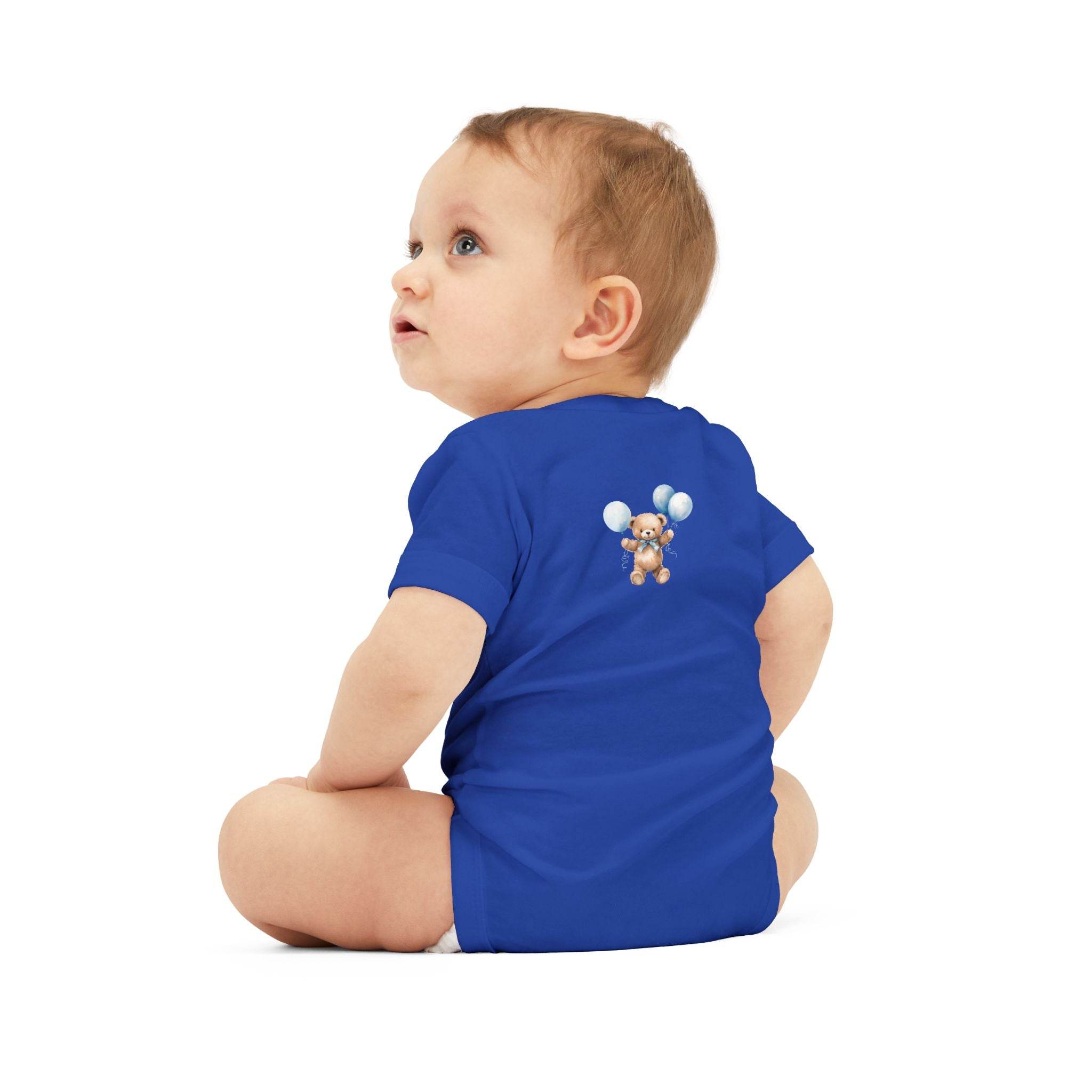 Baby wearing a blue eco-friendly baby onesie with a teddy bear and balloons print sitting on white background