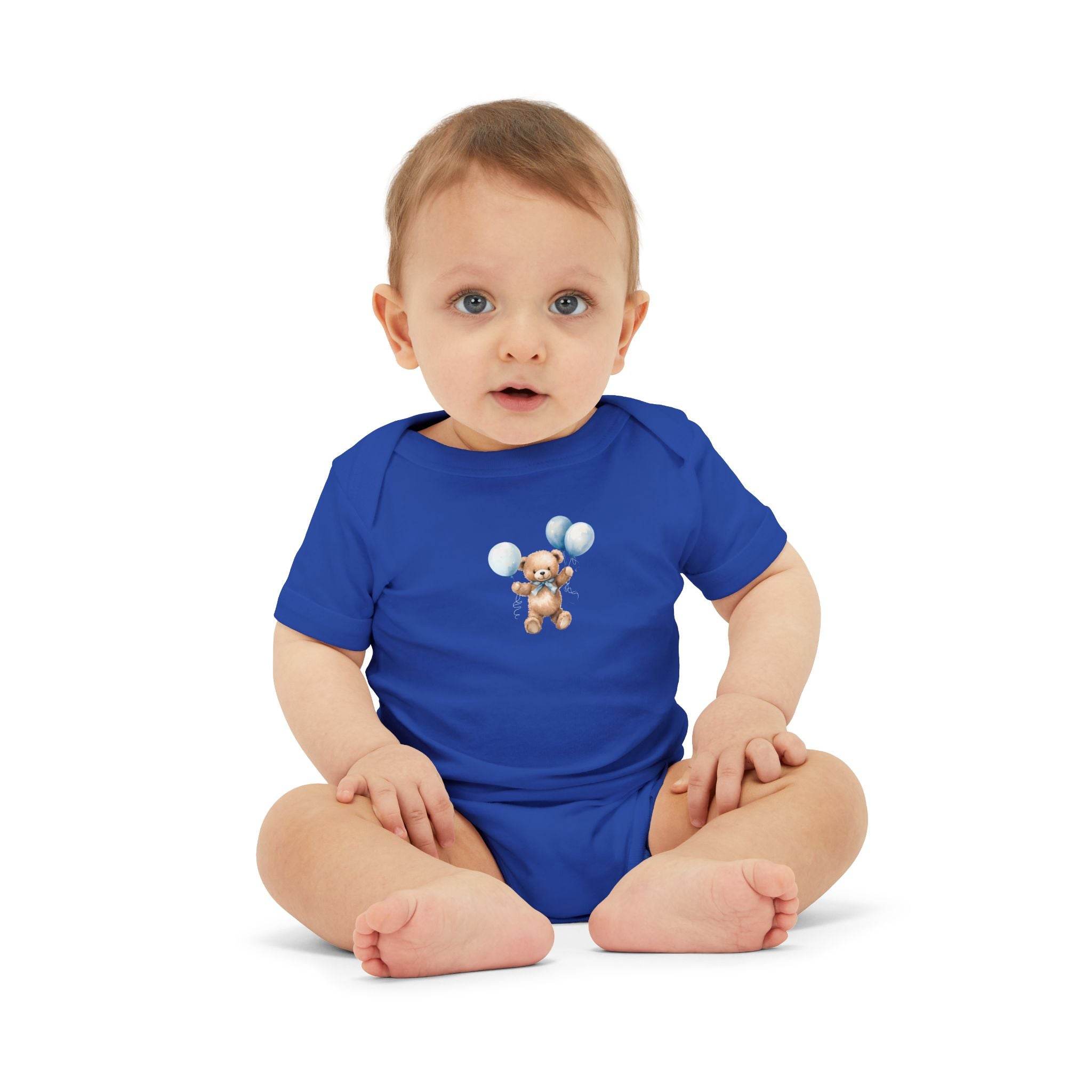 Baby wearing a blue eco-friendly baby onesie with teddy bear and balloon print sitting on white background