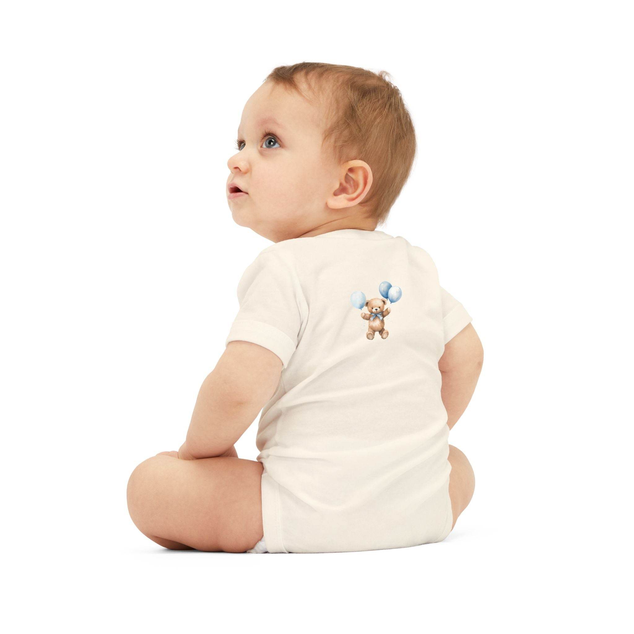 Baby wearing Printify eco-friendly baby onesie with teddy bear and balloon design sitting on white background