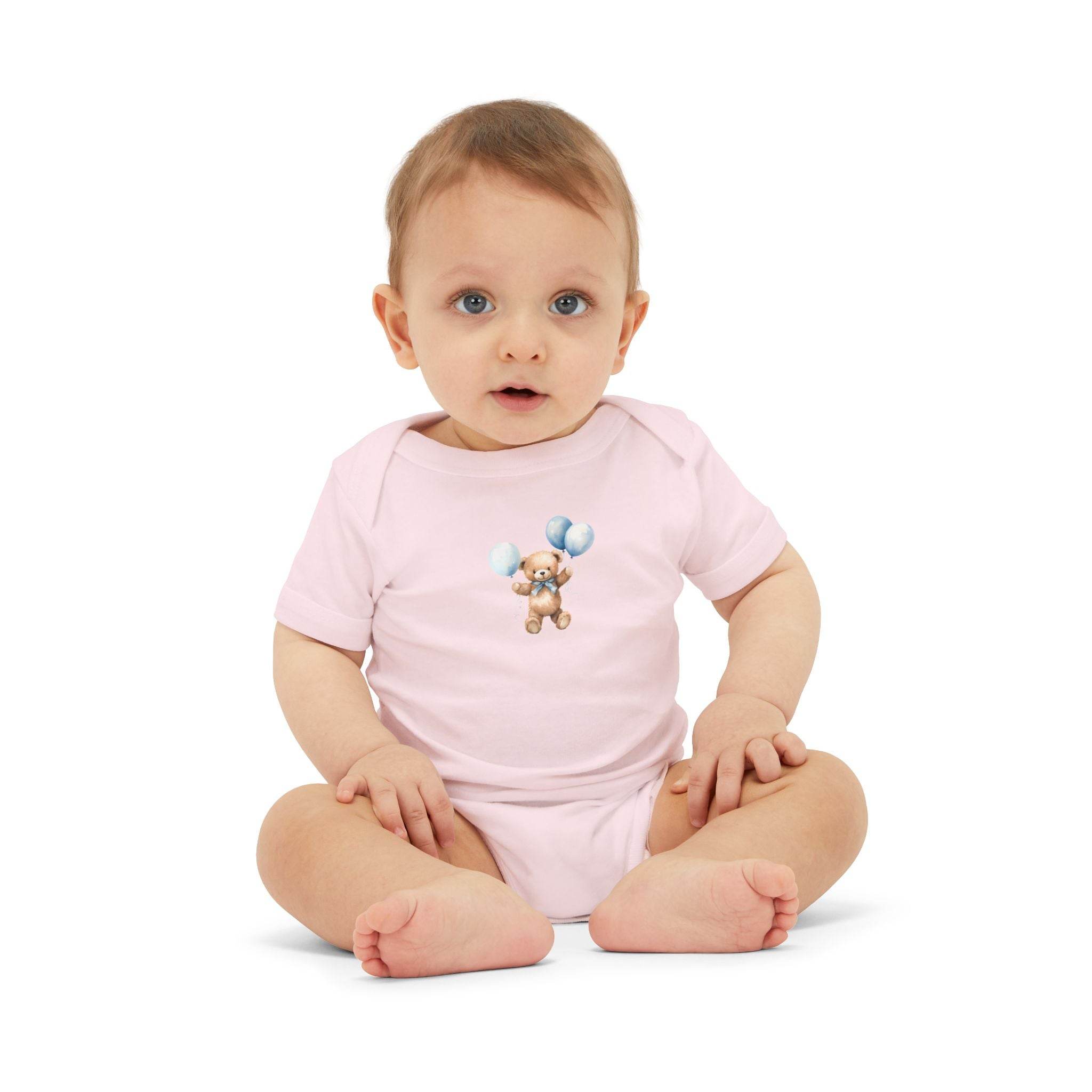 Baby wearing a light pink eco-friendly baby onesie with teddy bear and balloons print sitting on white background