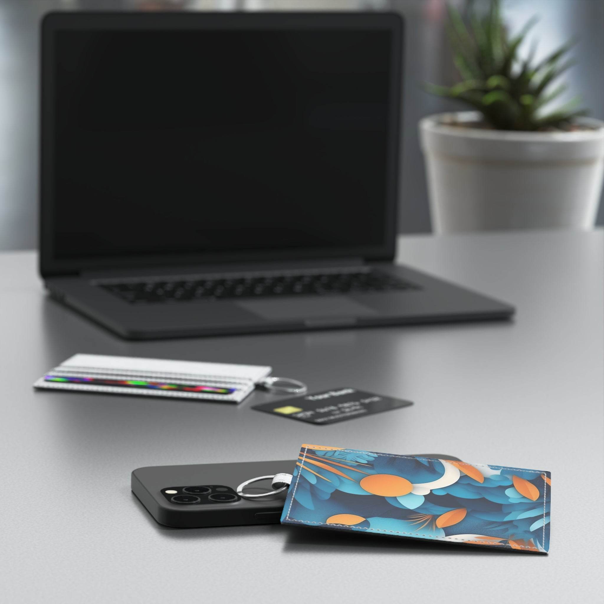 Printify eco-friendly card holder with blue and orange leaf pattern on a desk with laptop and keyring
