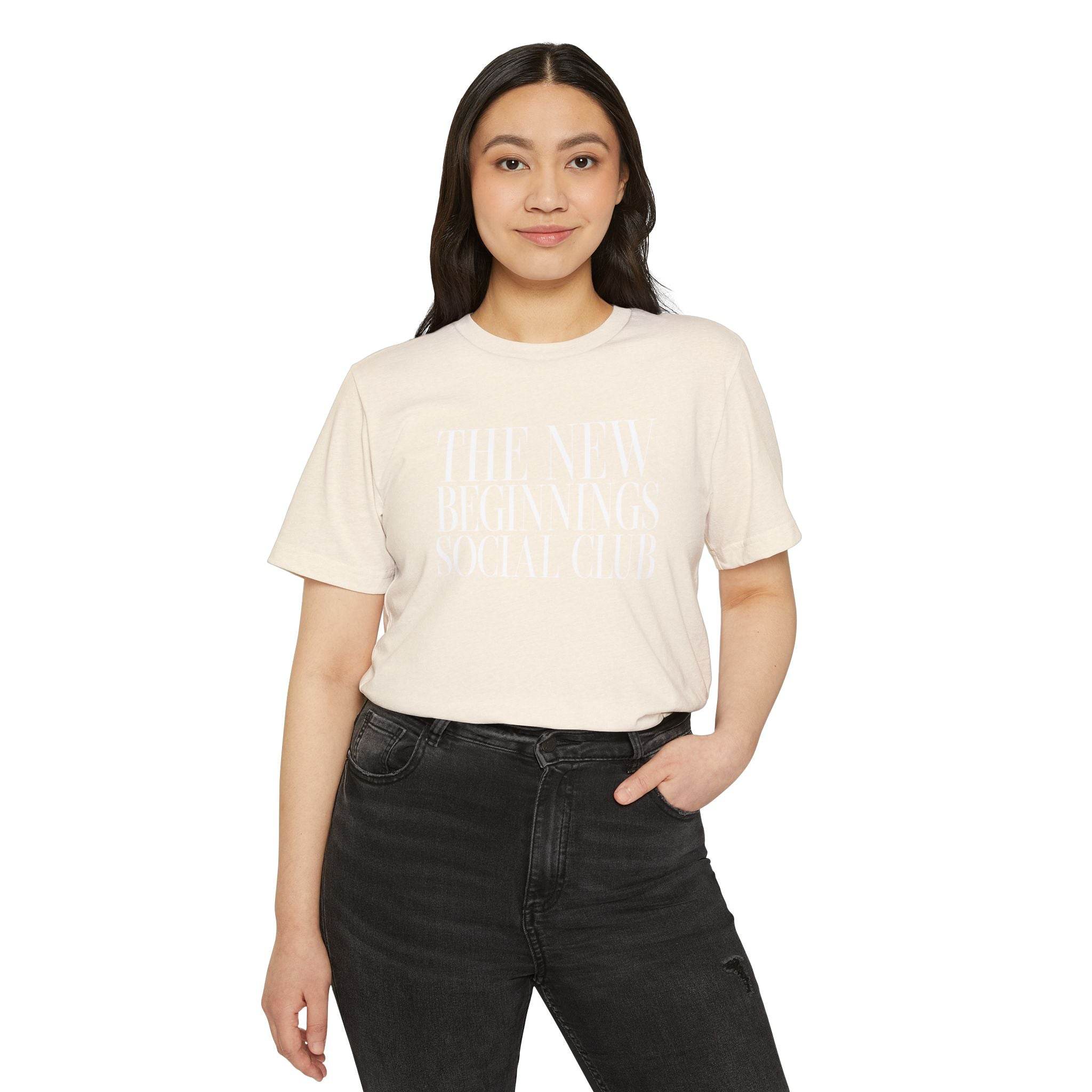 Printify eco-friendly fashion tee in cream with The New Beginnings Social Club text worn by woman