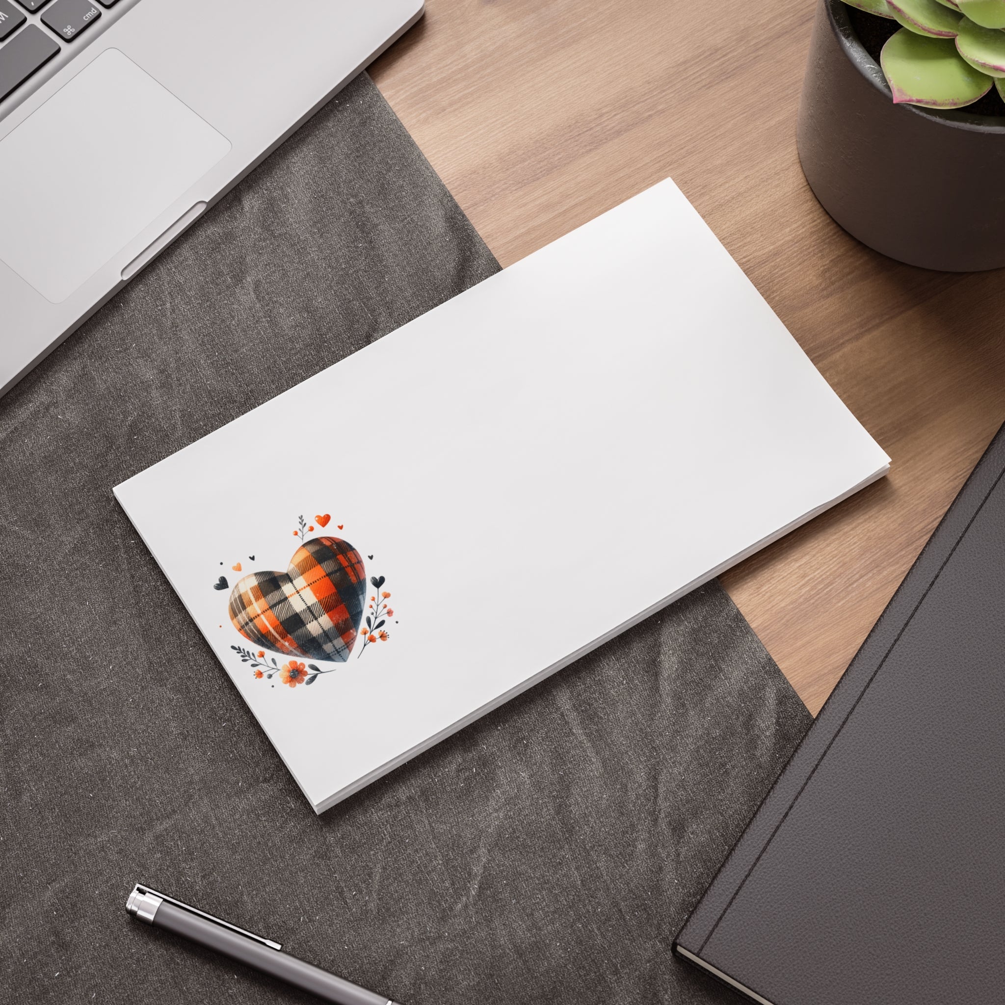 Printify eco-friendly note pads with heart design placed on a desk near laptop and plant