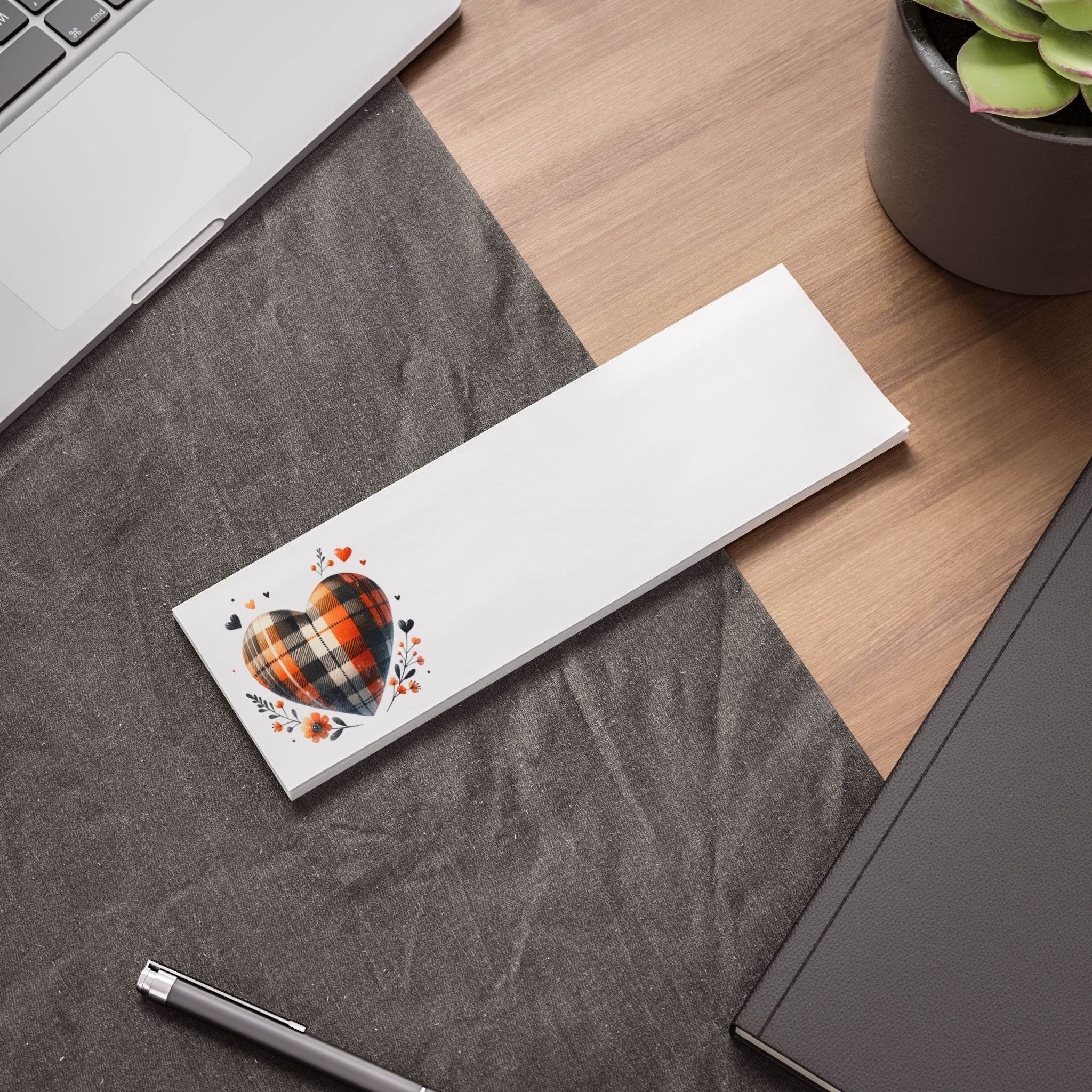 Eco-friendly note pads with plaid heart design placed on office desk next to laptop and notebook