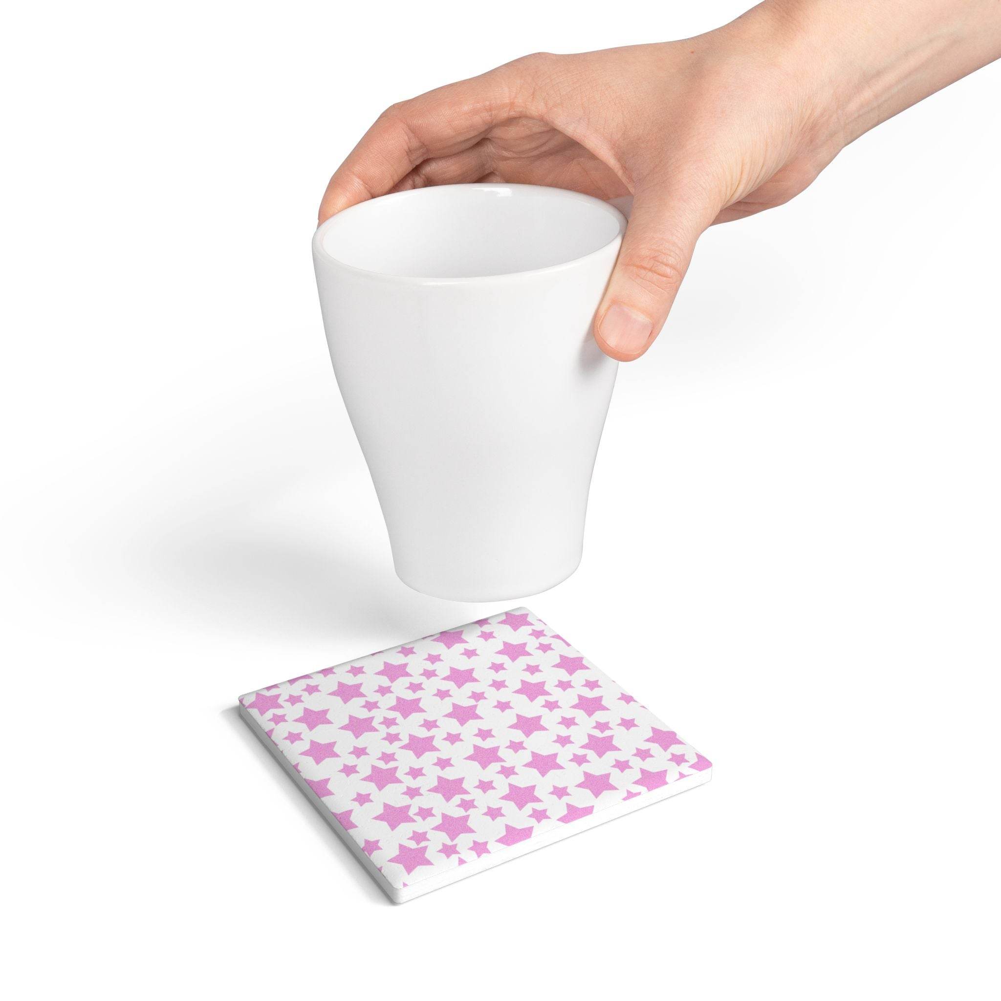Eco-friendly pink ceramic coaster with star pattern under white cup held by hand
