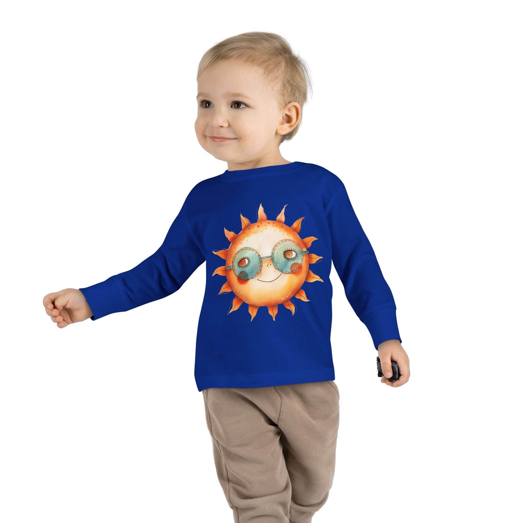 Toddler wearing blue eco-friendly toddler long sleeve shirt with sun graphic and beige pants