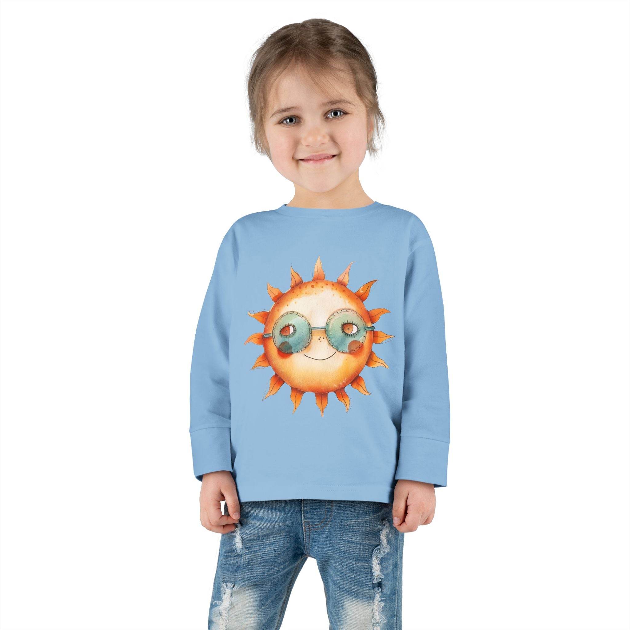 Printify eco-friendly toddler long sleeve shirt in light blue with sun graphic worn by smiling toddler