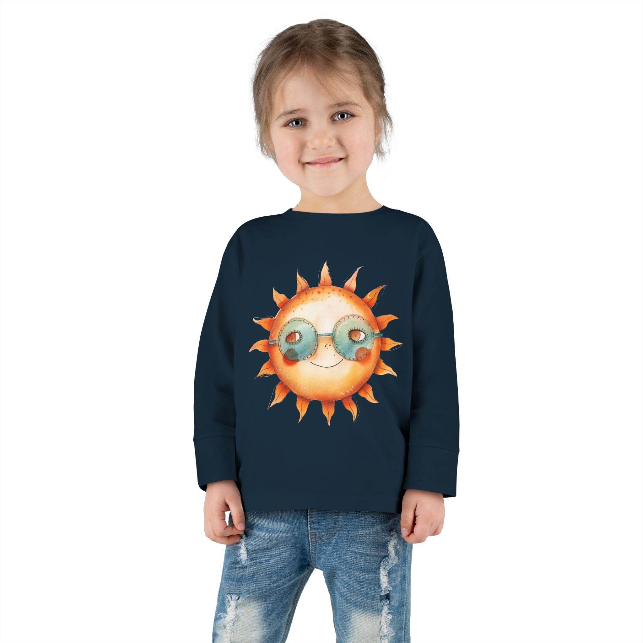 Printify eco-friendly toddler long sleeve shirt in navy blue with sun graphic worn by smiling child