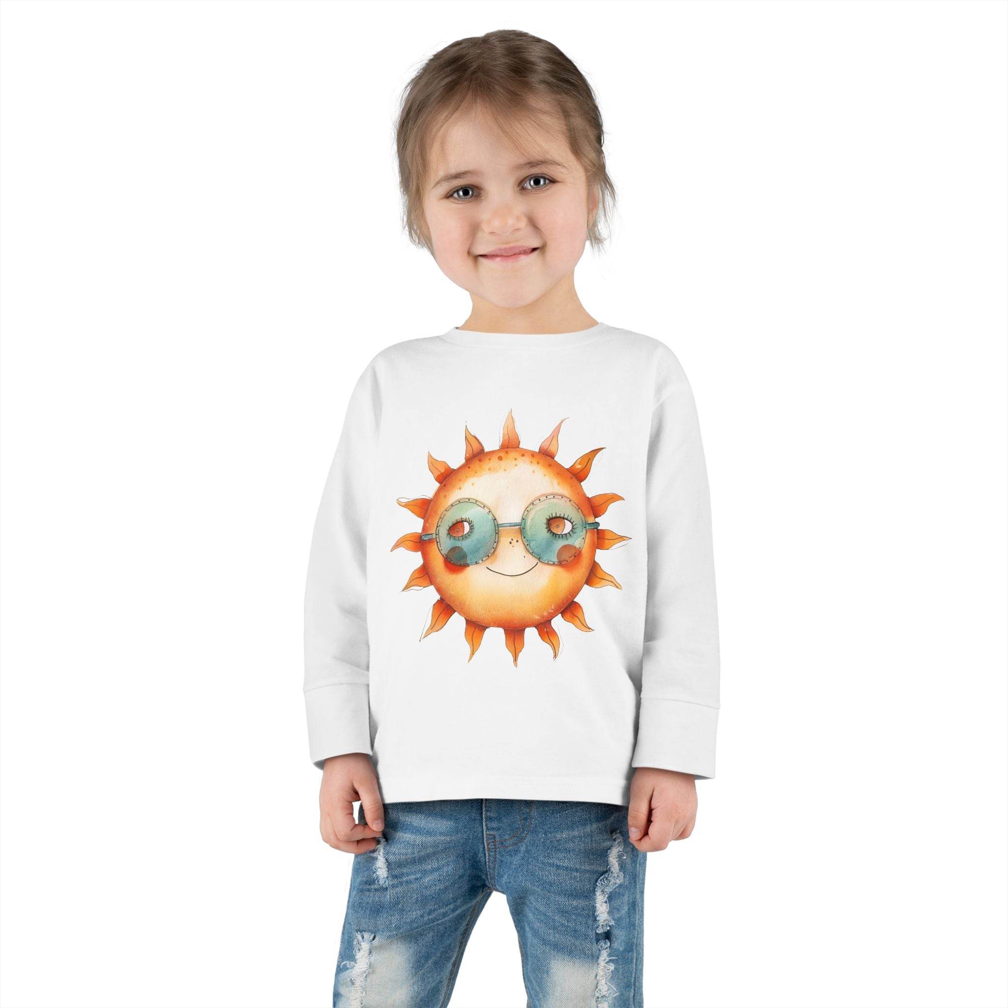 Smiling toddler wearing Printify eco-friendly toddler long sleeve shirt with sun graphic and sunglasses