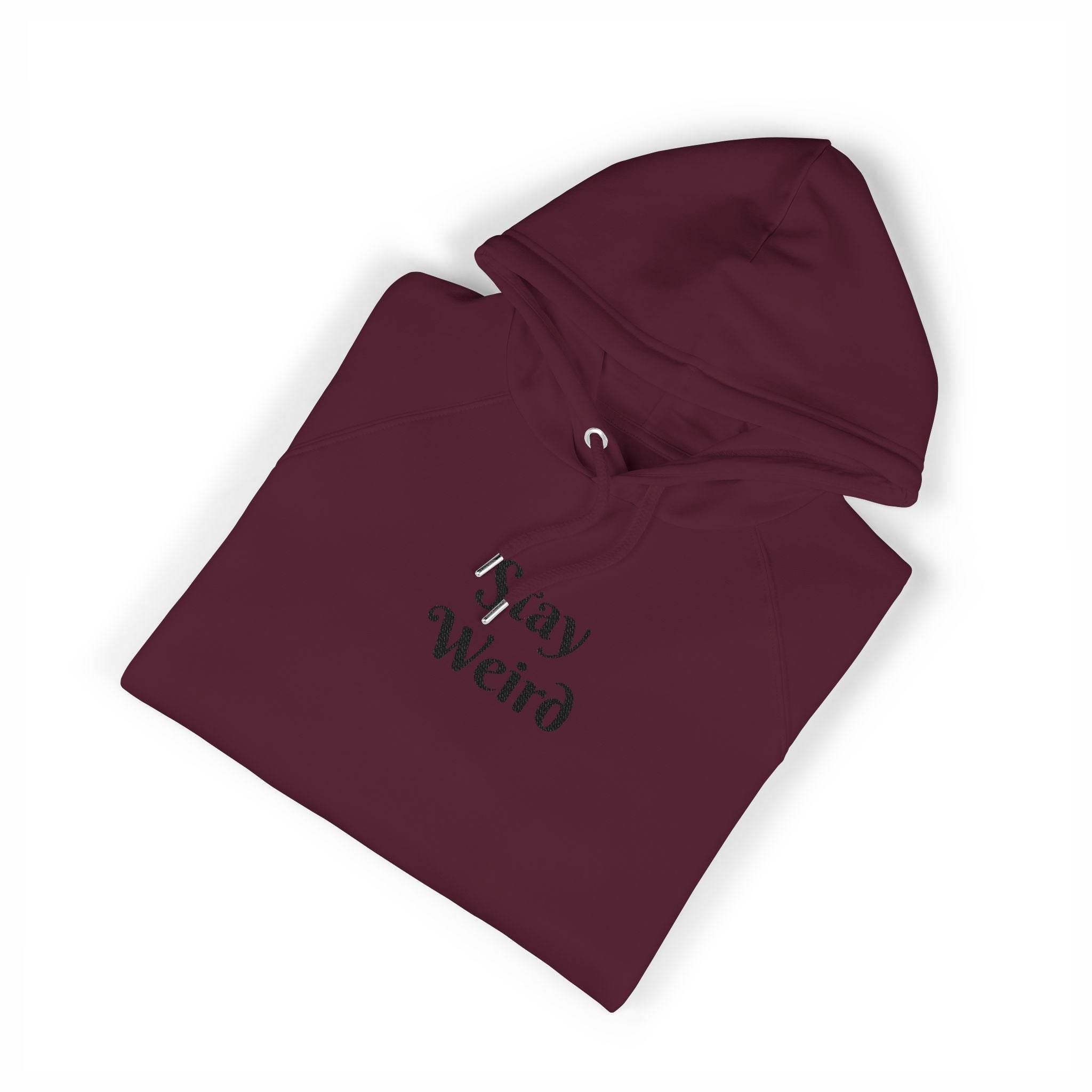 Maroon Printify eco friendly unisex hoodie with Stay Weird text design folded neatly