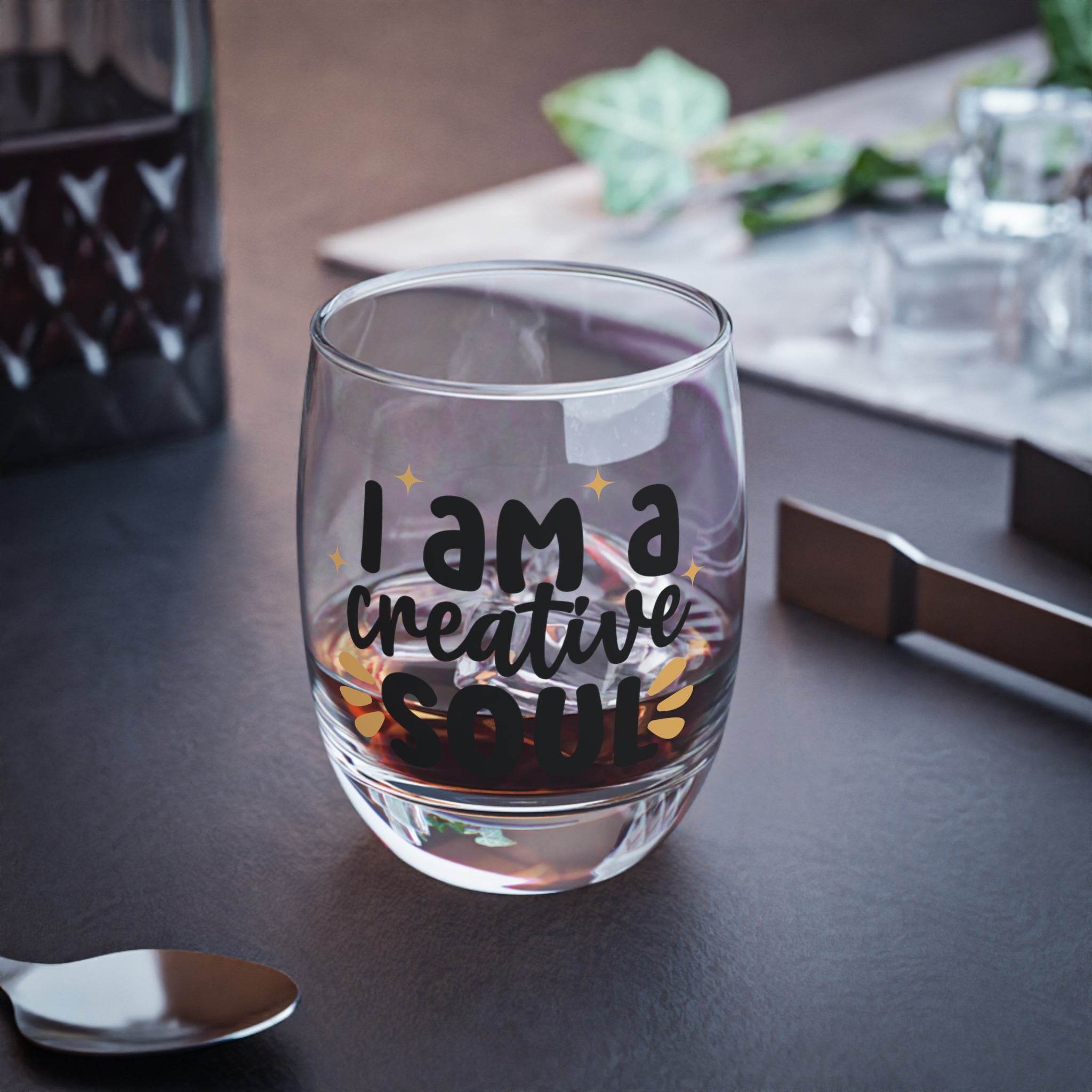 Printify eco-friendly whiskey glass with I am a creative soul text filled with whiskey on a dark surface