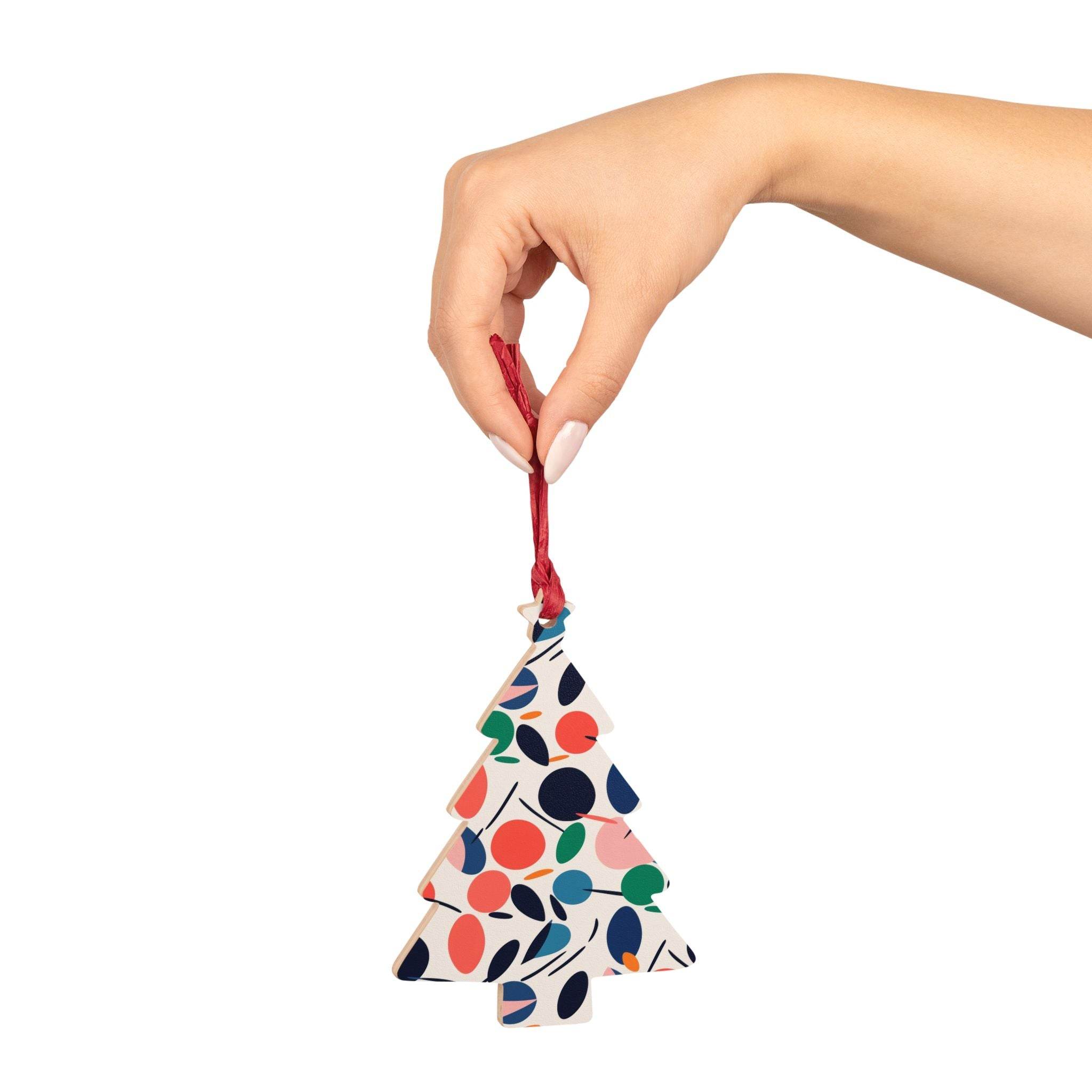 Hand holding eco-friendly wooden ornaments shaped like a Christmas tree with colorful abstract design