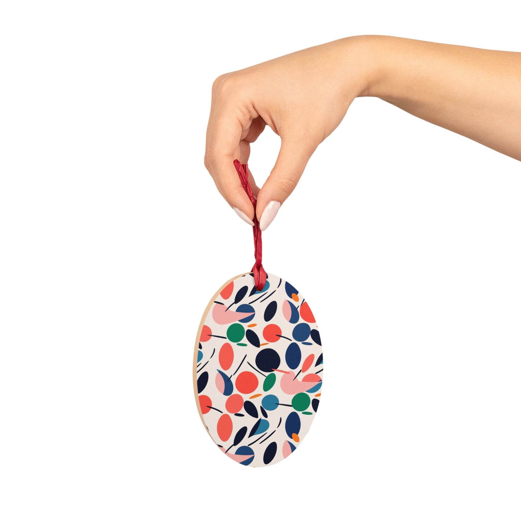 Hand holding colorful eco-friendly wooden ornaments with red ribbon for seasonal decorations
