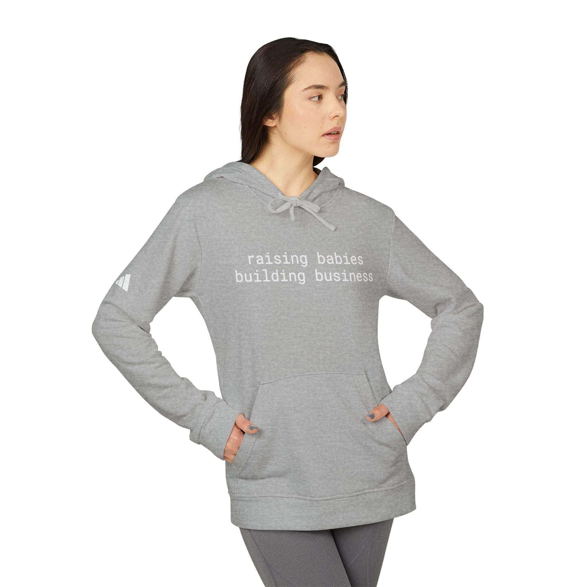 Printify gray eco-friendly unisex fleece hoodie worn by model with kangaroo pocket and text raising babies building business