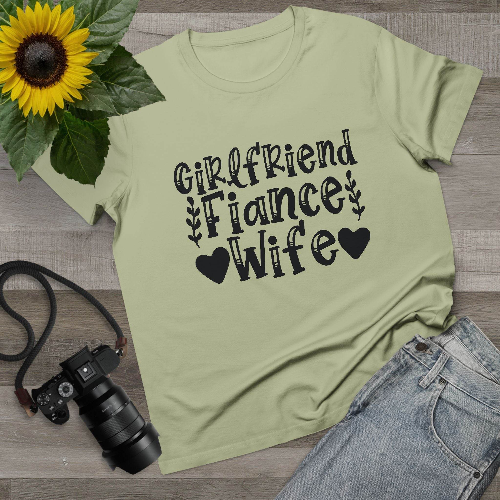 Printify sage green tee laid flat with Girlfriend Fiance Wife text and sunflower props eco-friendly women's relationship tee
