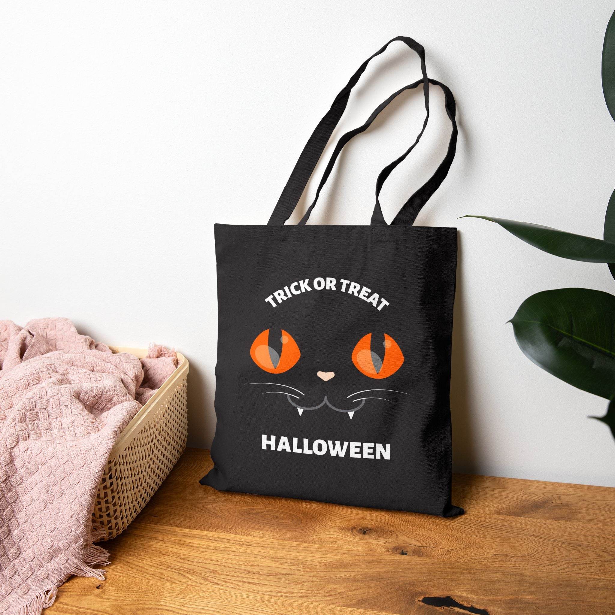 Black eco-friendly Halloween tote bag by Printify with orange cat eyes and trick or treat text