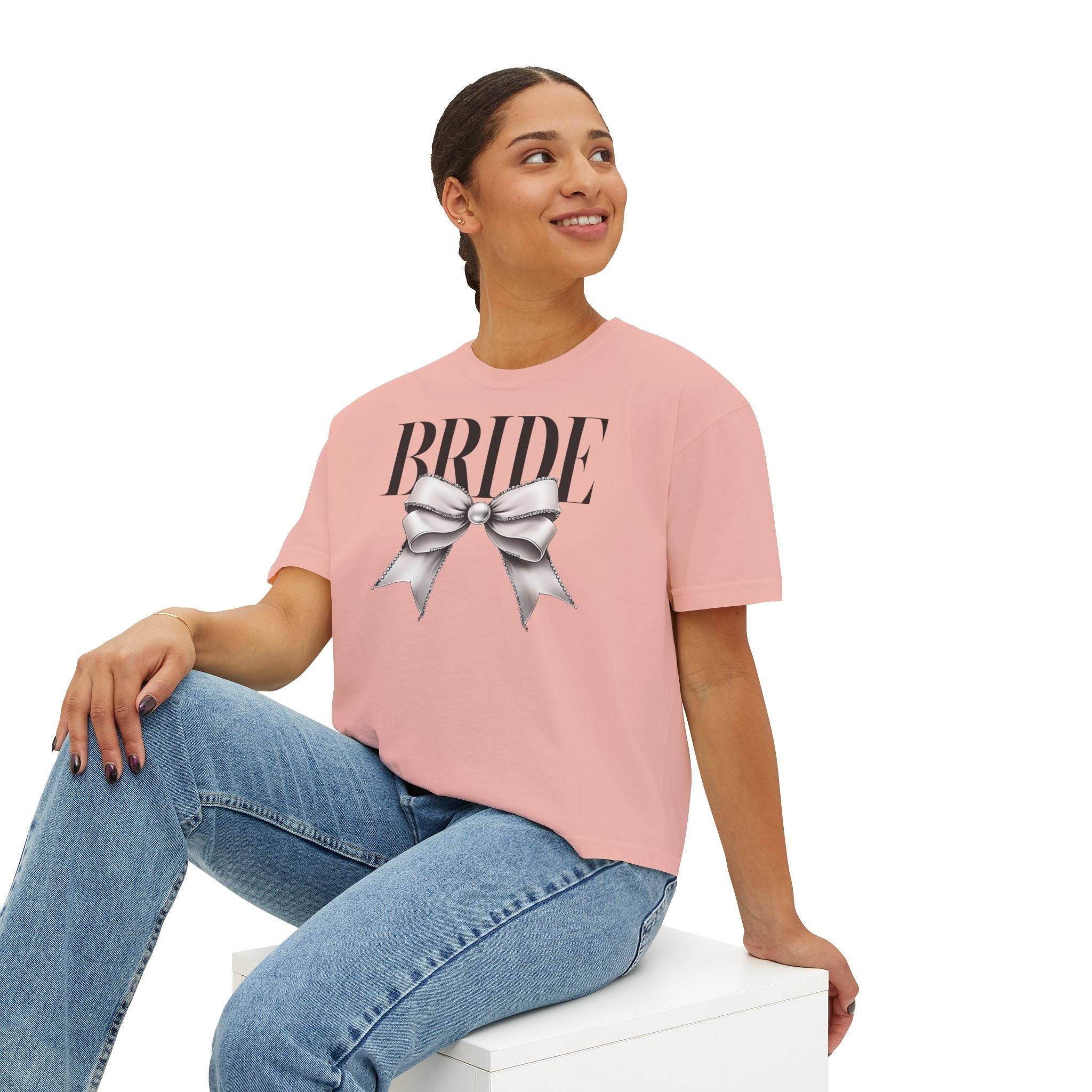 Printify pink tee with BRIDE text and silver bow graphic worn by seated model in jeans eco-friendly bridal t-shirt