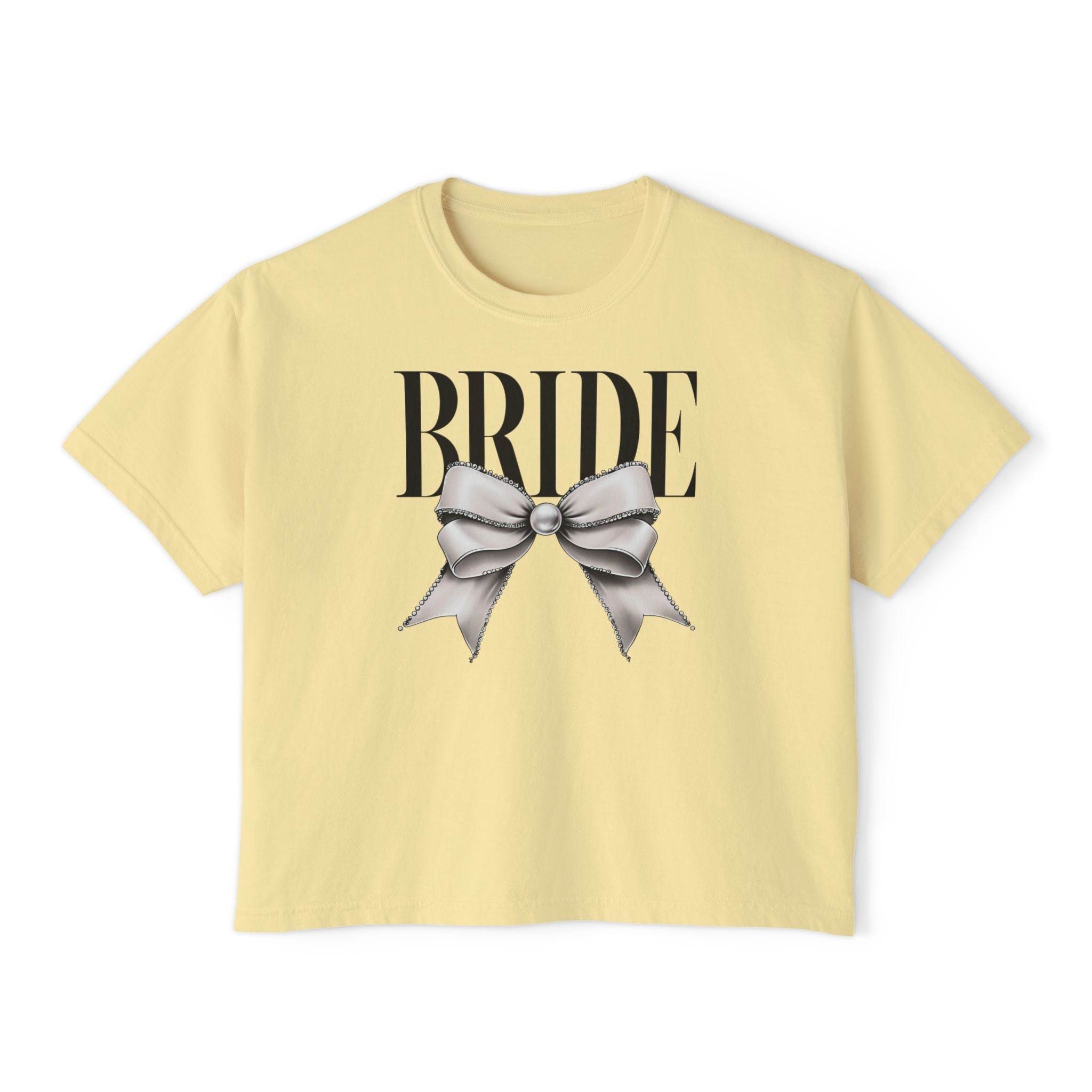 Printify pale yellow cropped T shirt reading BRIDE with large silver bow graphic on front eco-friendly bridal t-shirt