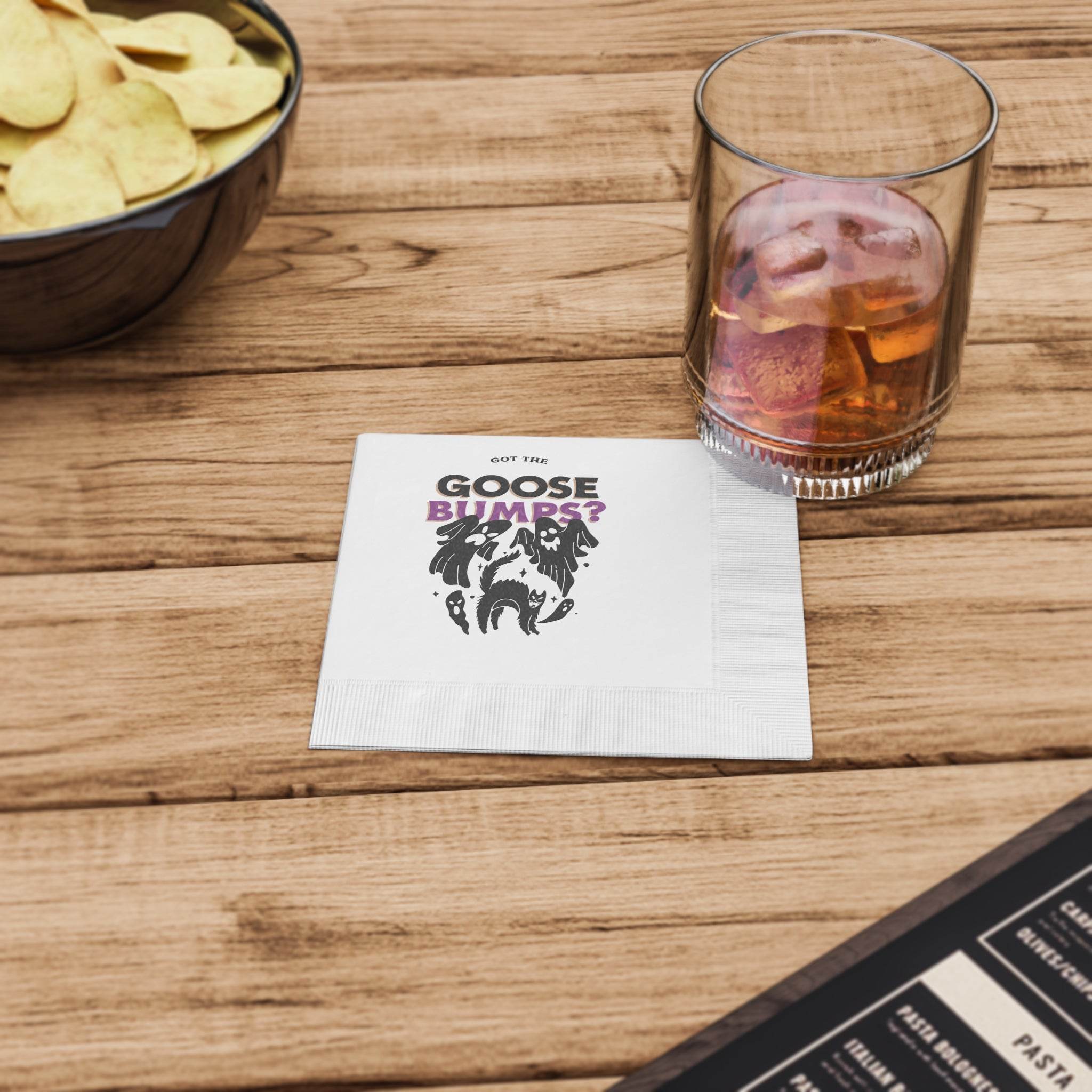 Printify eco-friendly Halloween napkins with spooky goose bumps print on wooden table beside drink and chips for party use