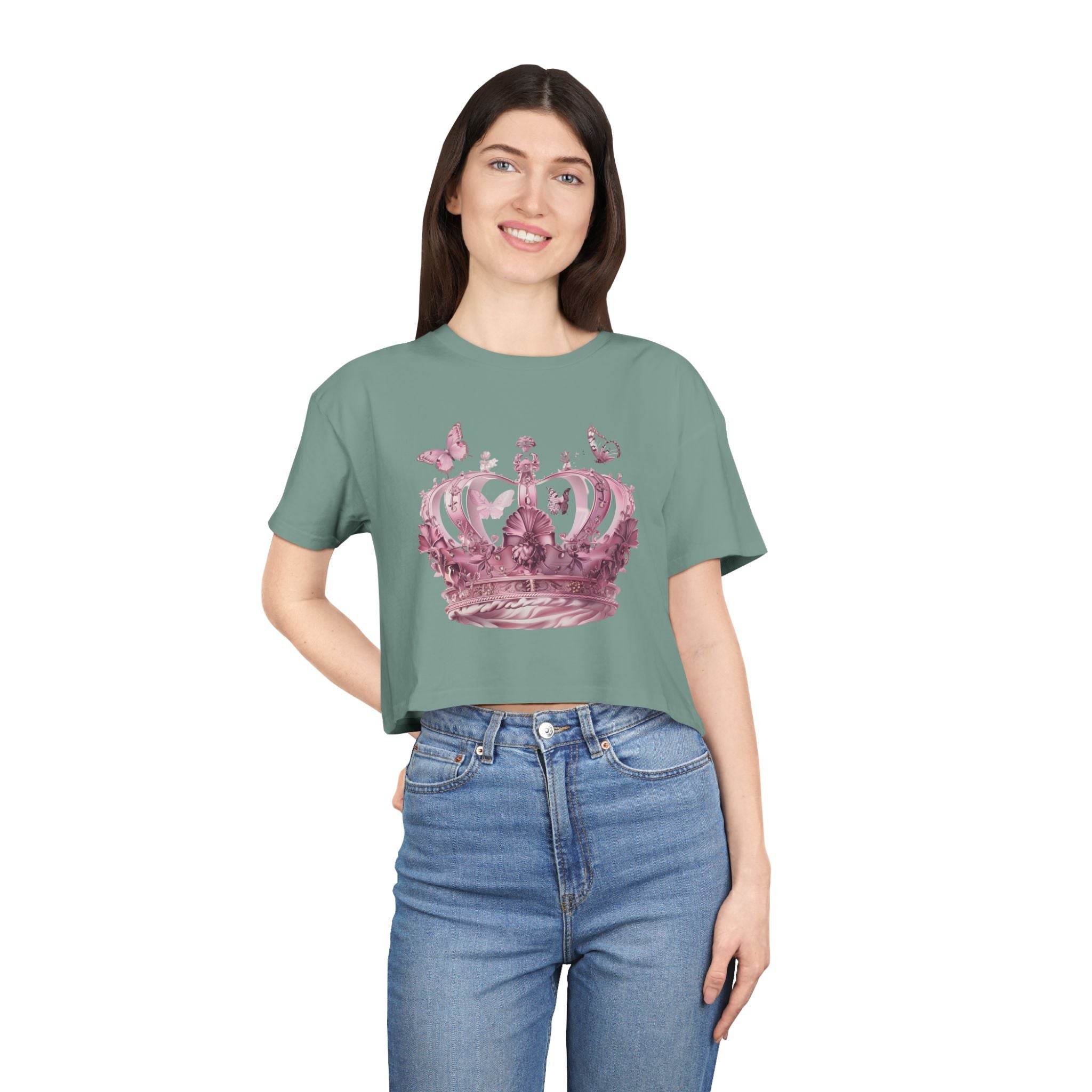 Woman wearing a Petal & Crown eco crop shirt by Printify with a pink crown graphic and blue jeans