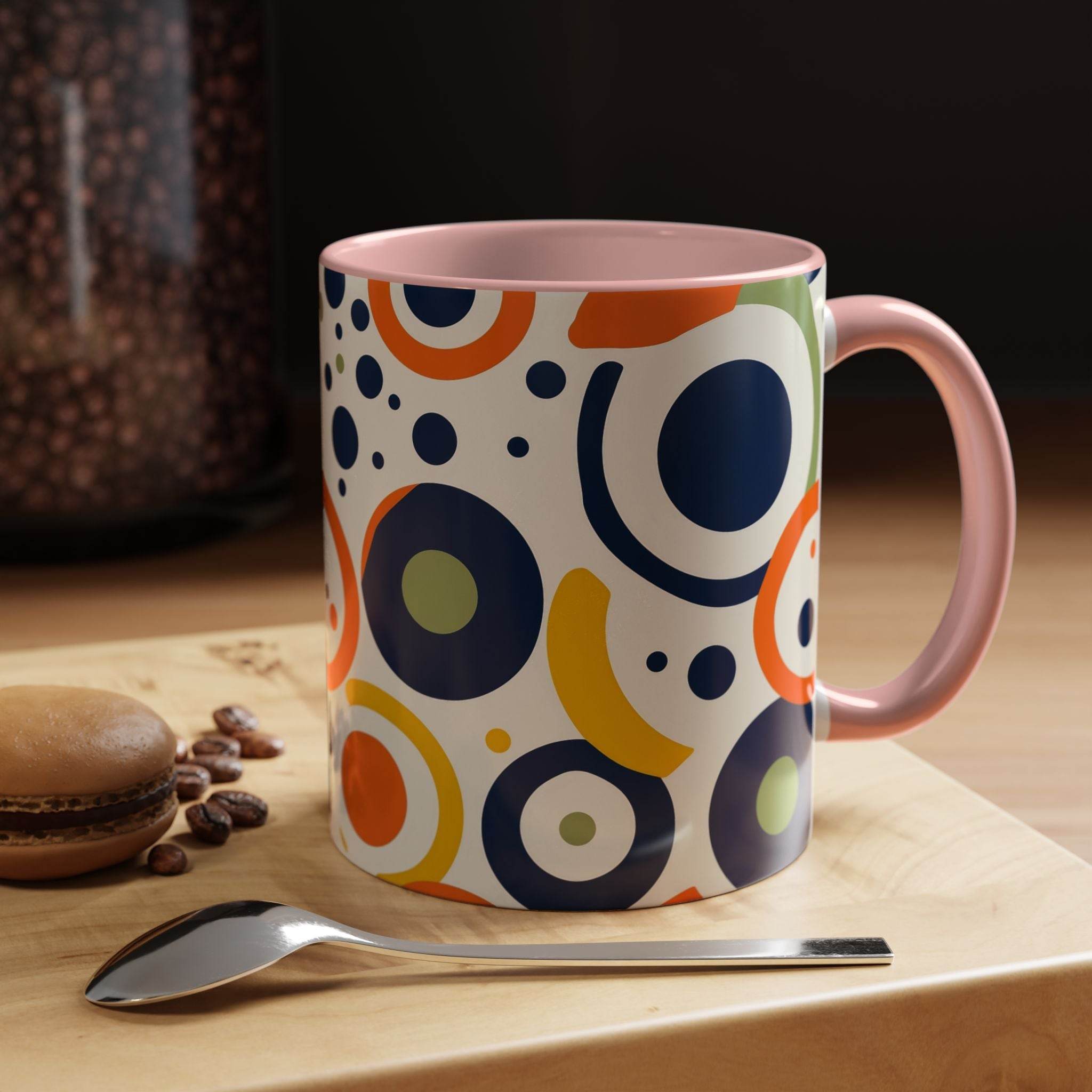 Printify pop art coffee mug with colorful abstract circle patterns and pink handle on wooden table