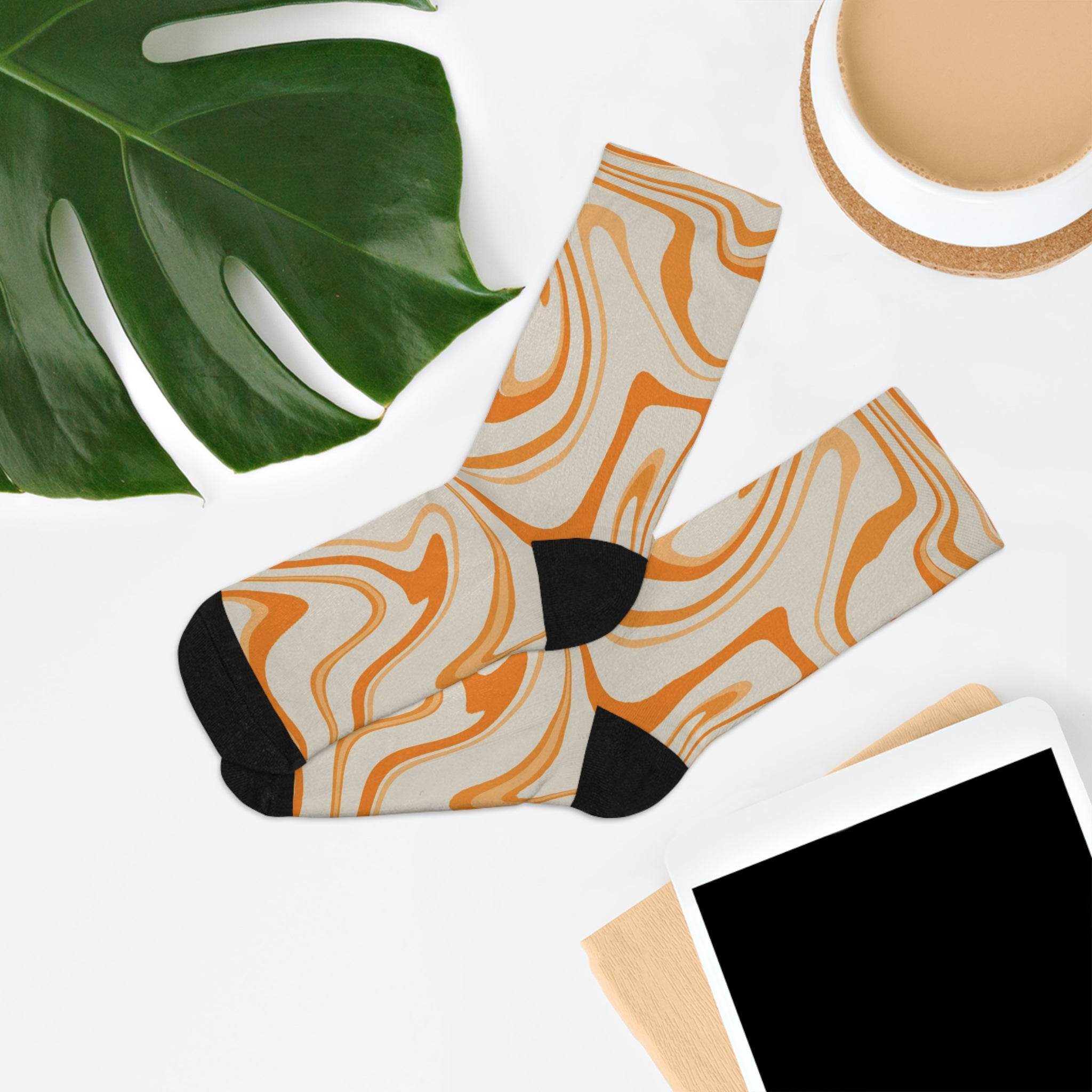 Printify recycled poly socks with orange swirl pattern and black heels and toes laid flat on white surface