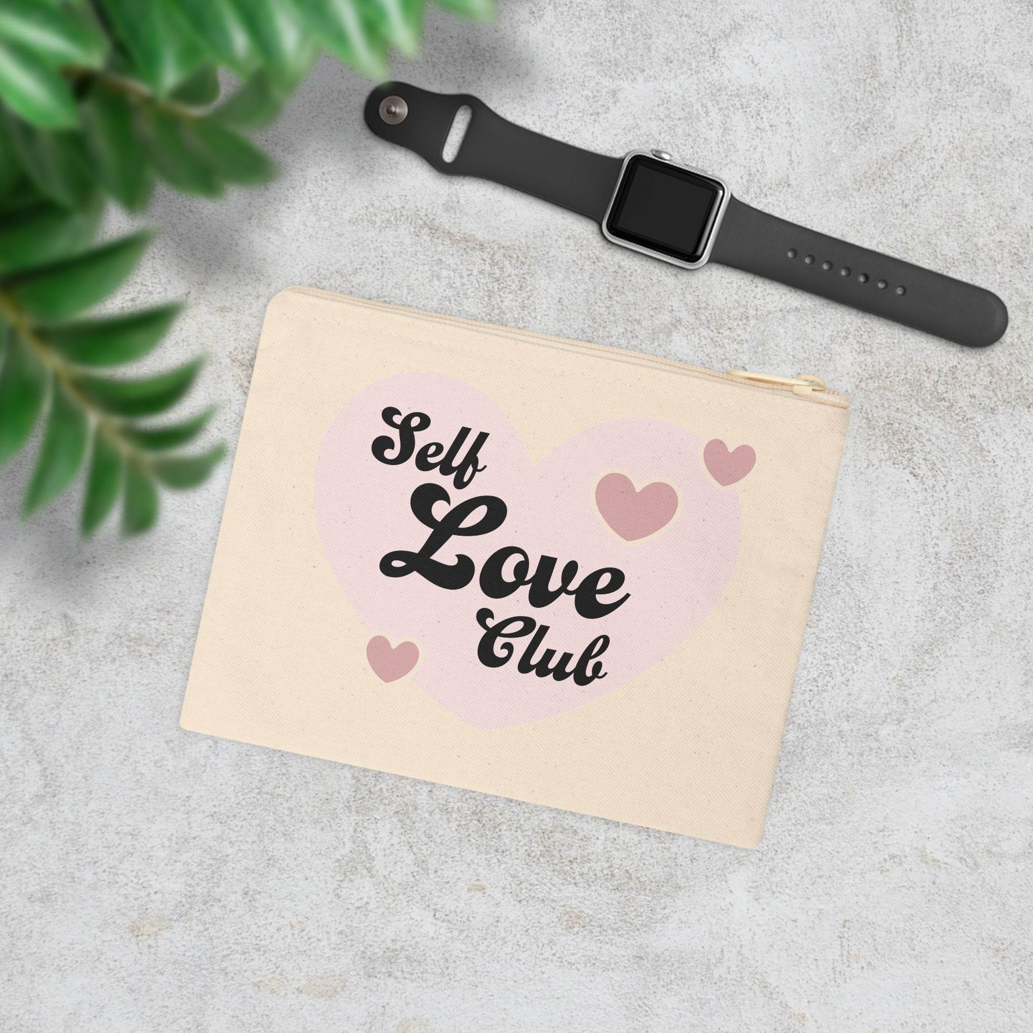 Printify eco-friendly zipper pouch with Self Love Club heart design next to a black smartwatch