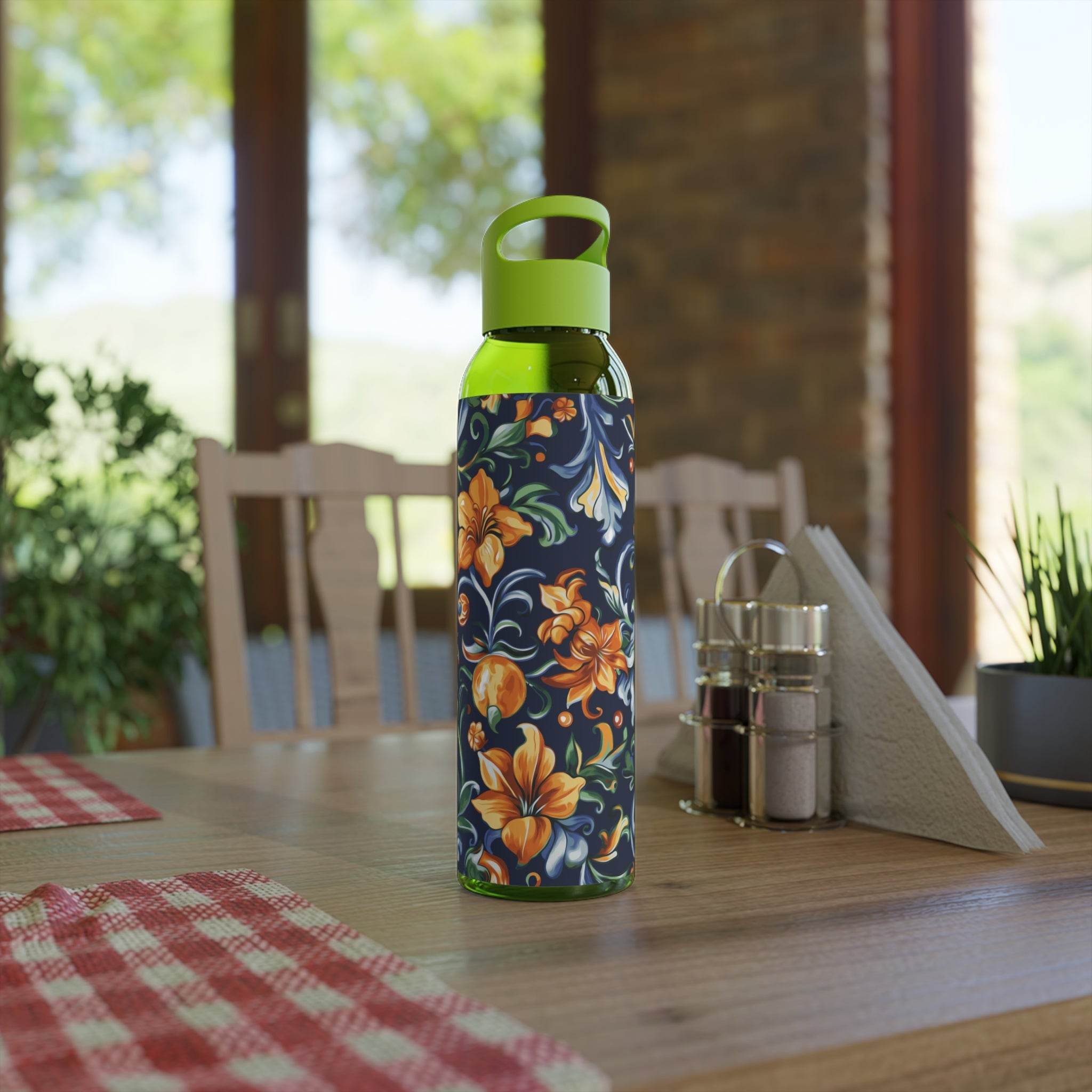 Stylish eco water bottle with floral design and green cap placed on wooden table indoors
