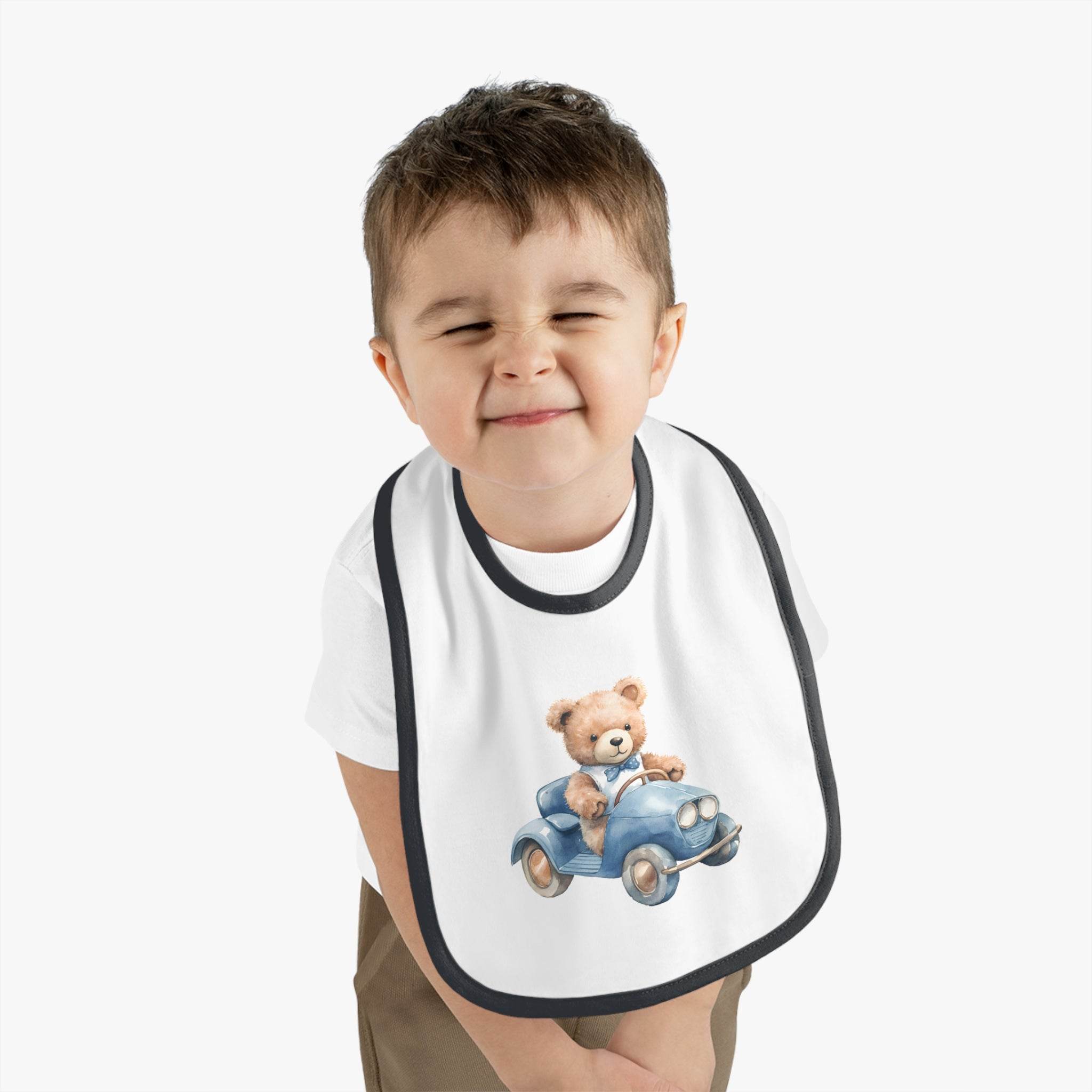 Toddler wearing a Printify sustainable baby bib with a cute teddy bear driving a blue car design
