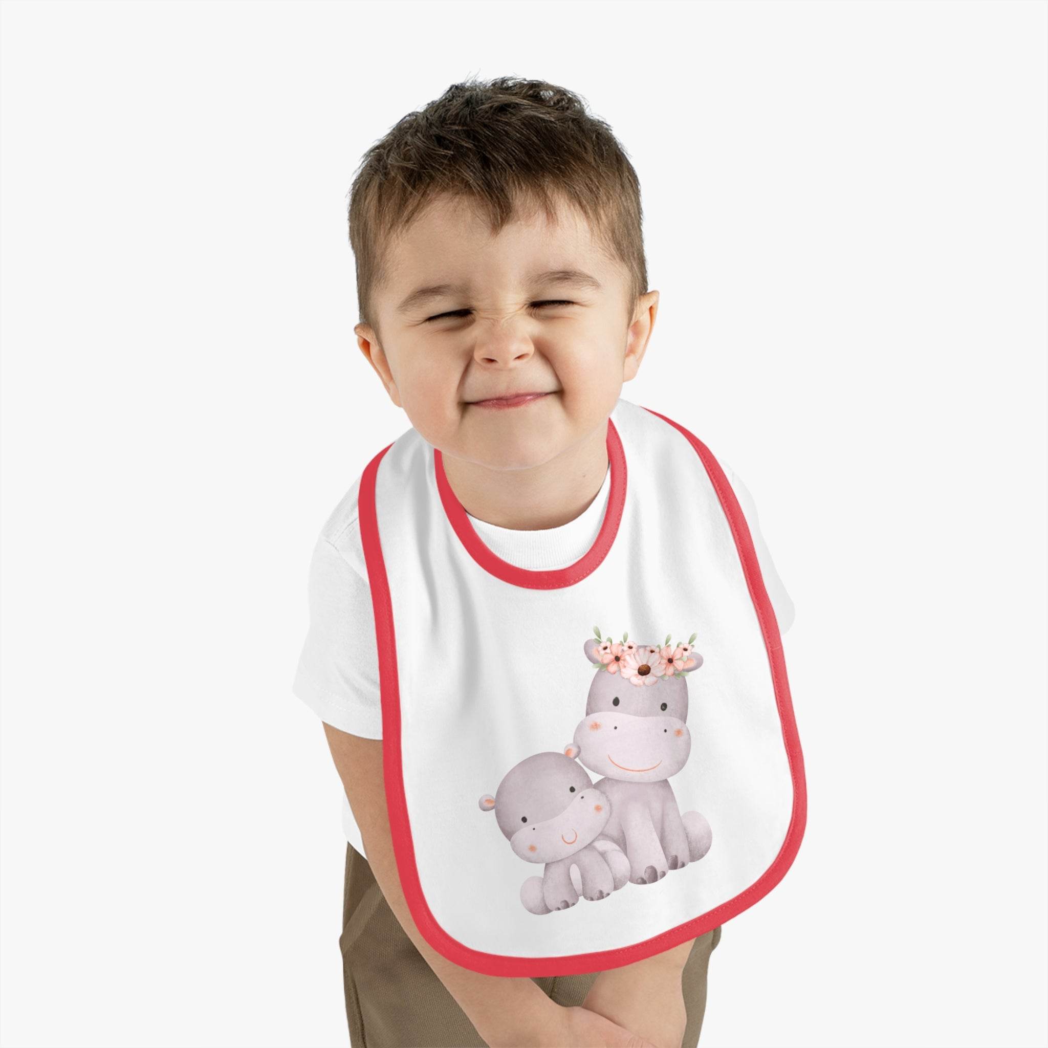 Toddler wearing a sustainable baby jersey bib with red trim and cute hippo print from Printify