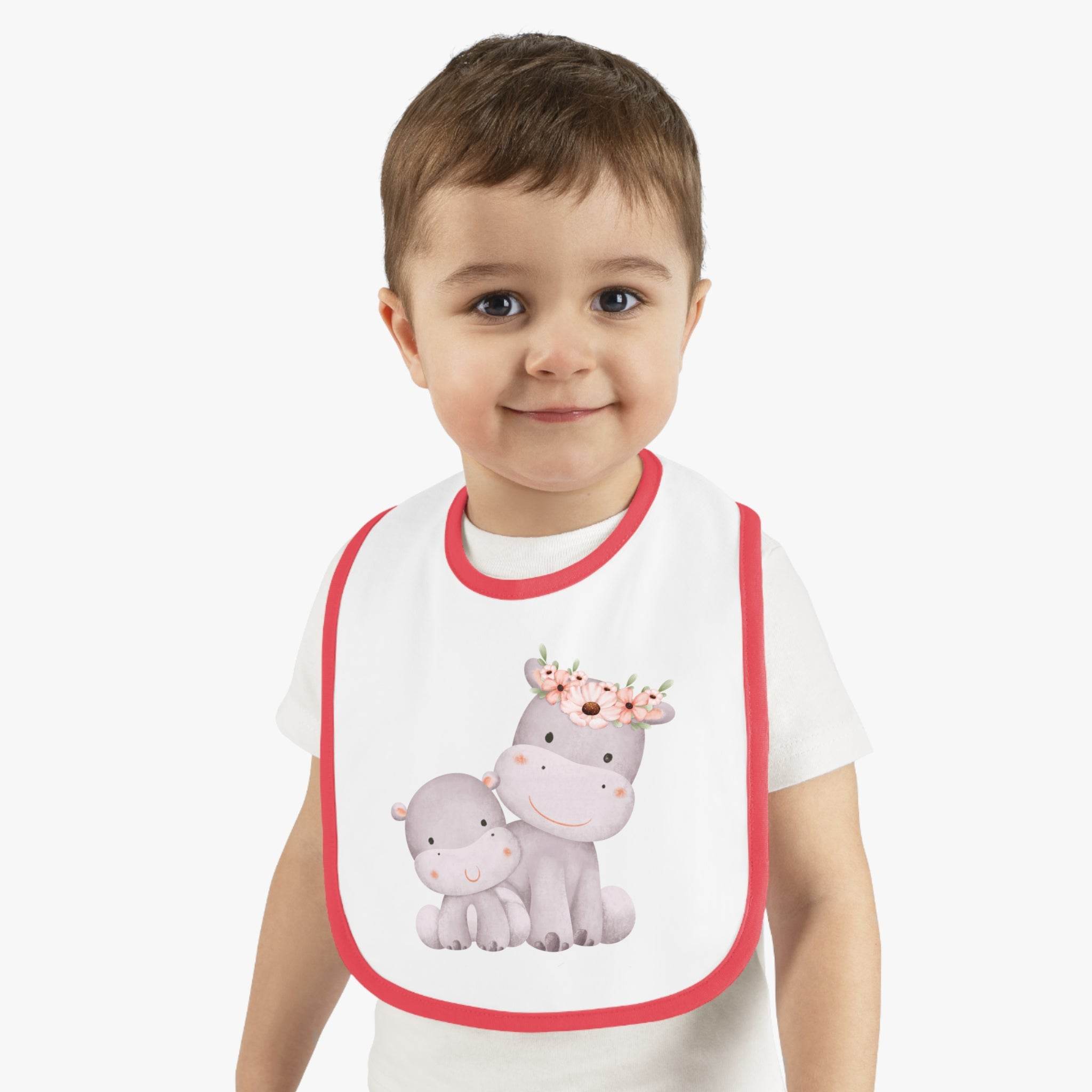 Toddler wearing Printify sustainable baby jersey bib with cute hippo and floral design and red trim