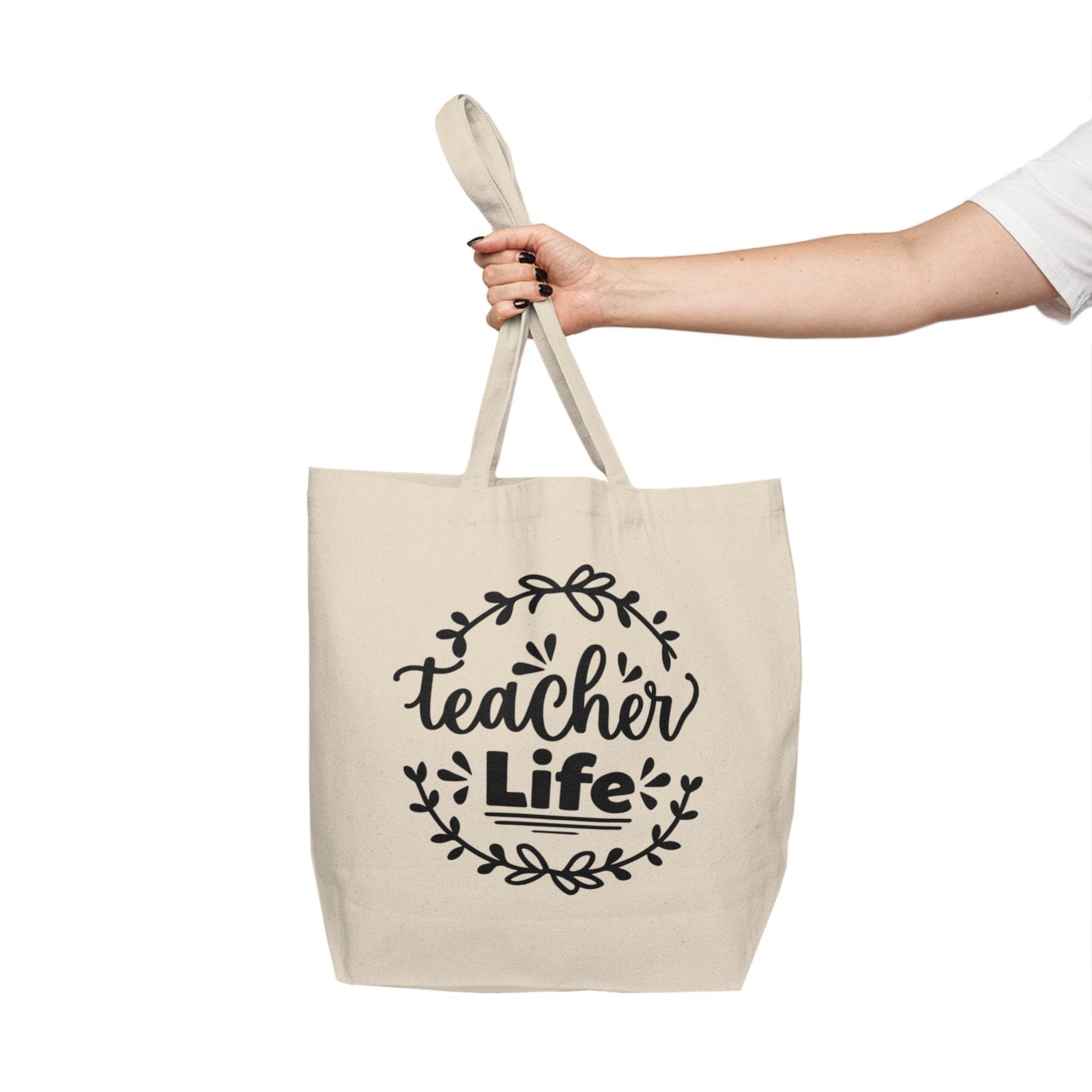 Printify teacher canvas tote bag in cream color with teacher life design held by a hand