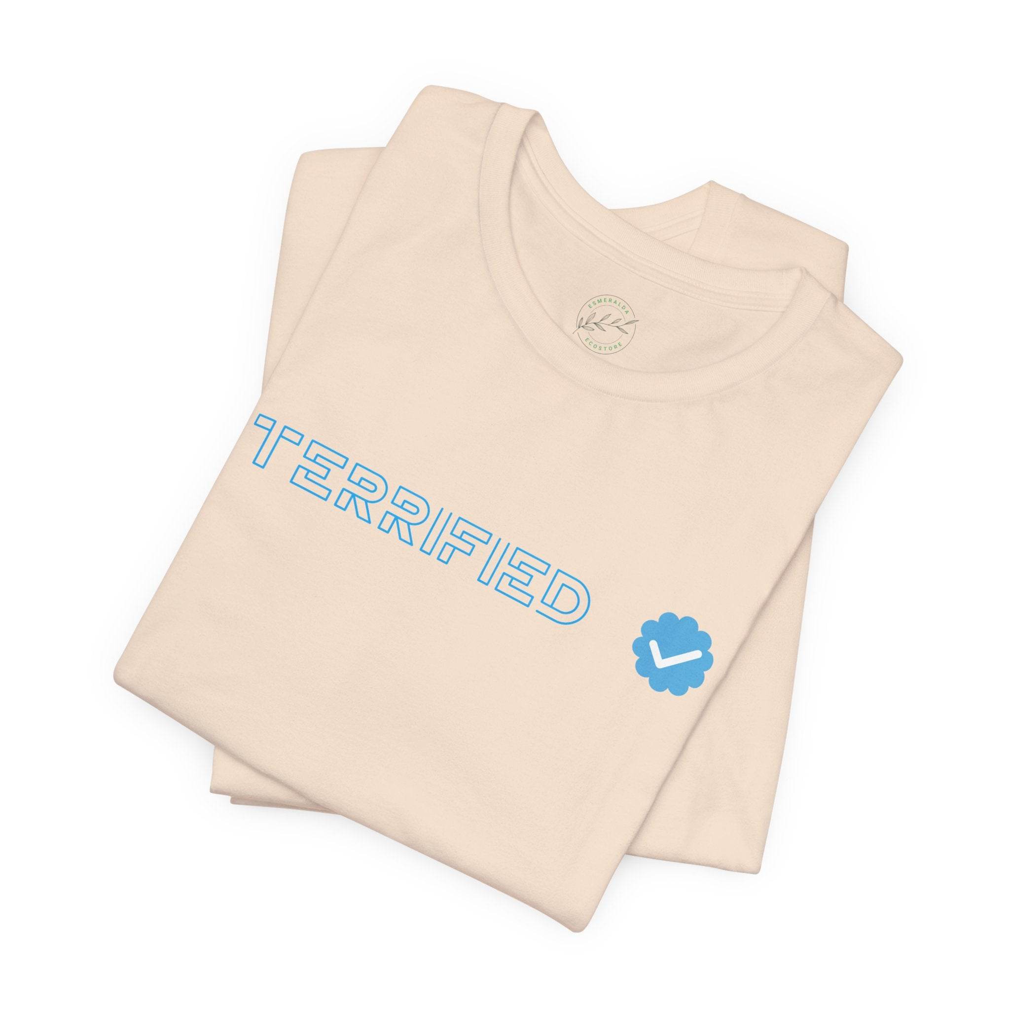 Folded beige Printify T-shirt with blue outlined text terrified and blue checkmark logo