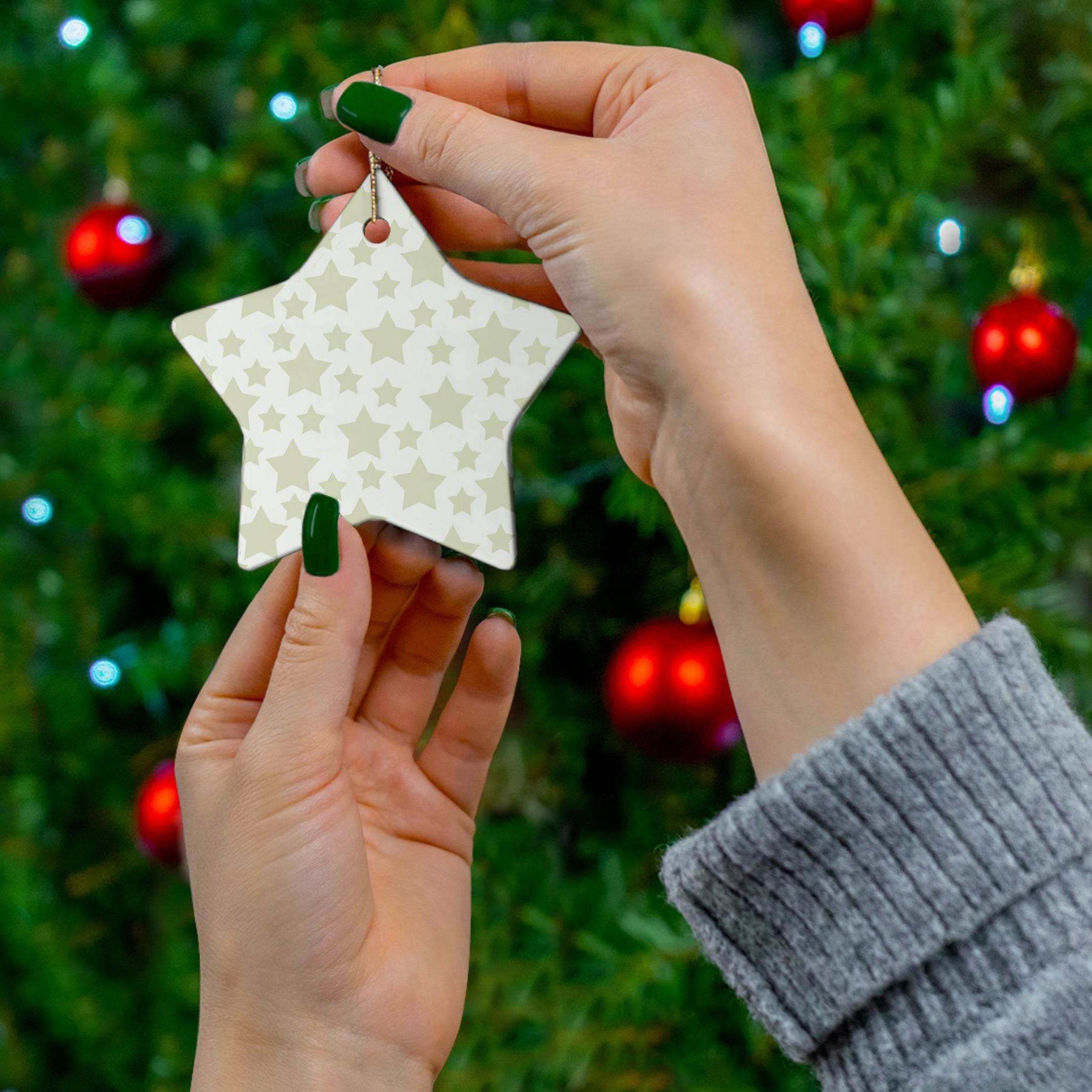Hands holding a twinkling stars holiday decoration star ornament in front of a decorated Christmas tree