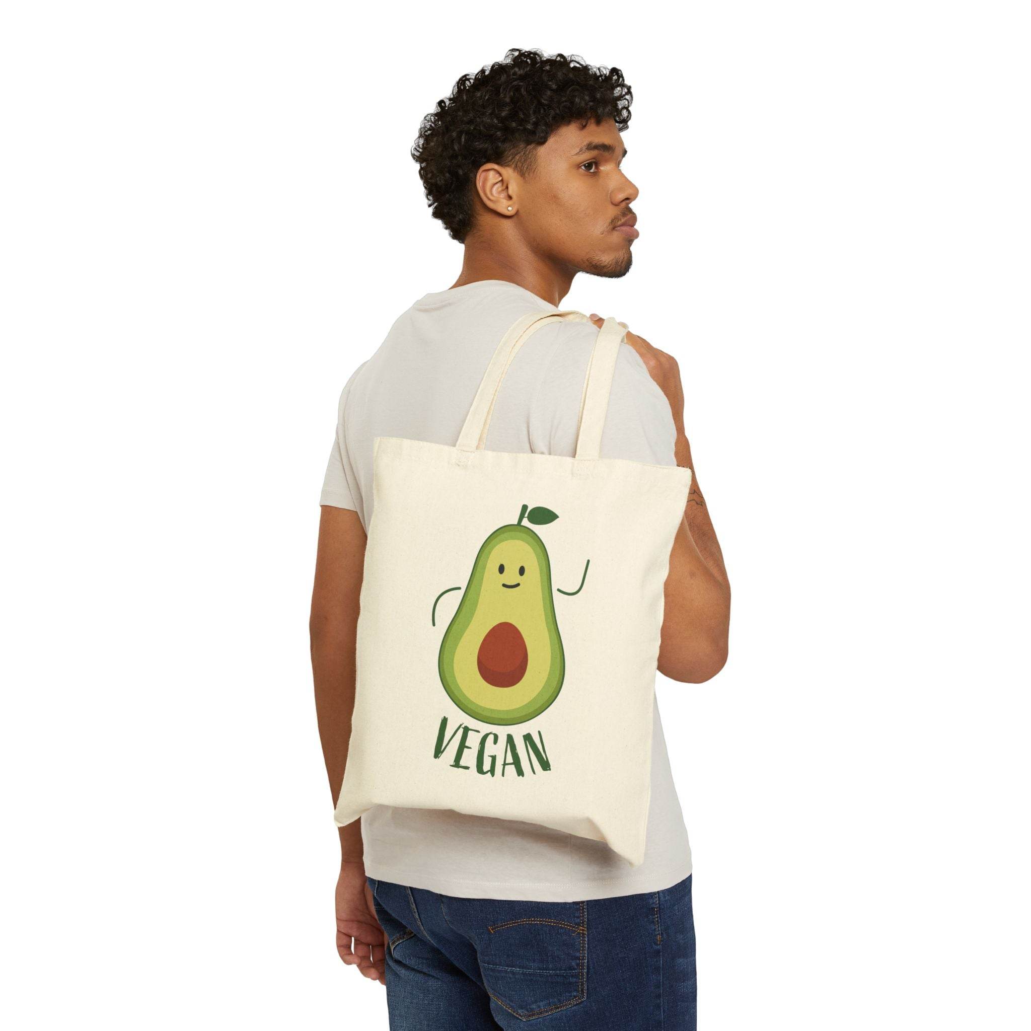 Man carrying eco-friendly cotton tote bag with a cute vegan avocado design printed on the front