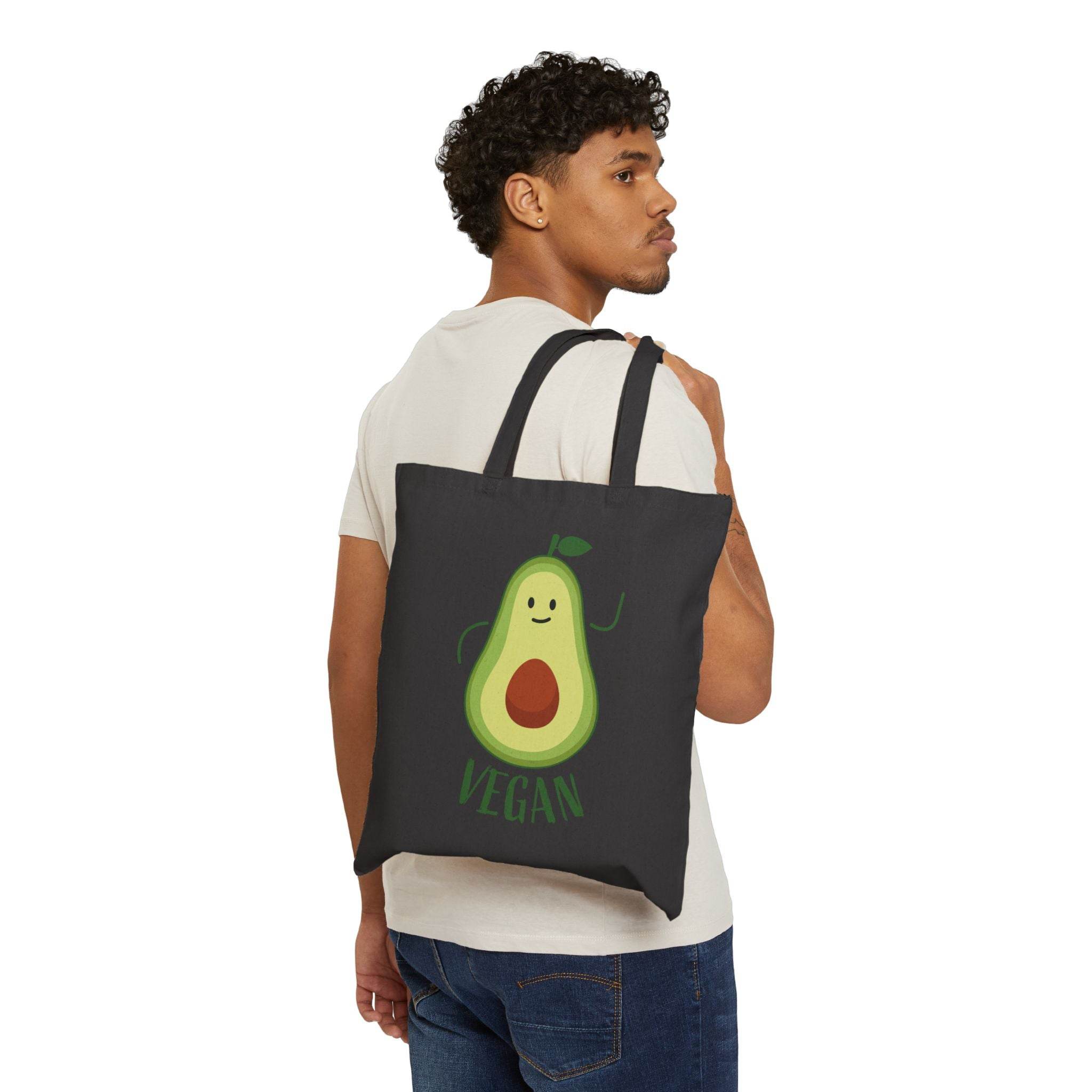 Man carrying eco-friendly cotton tote bag with smiling avocado and vegan text design