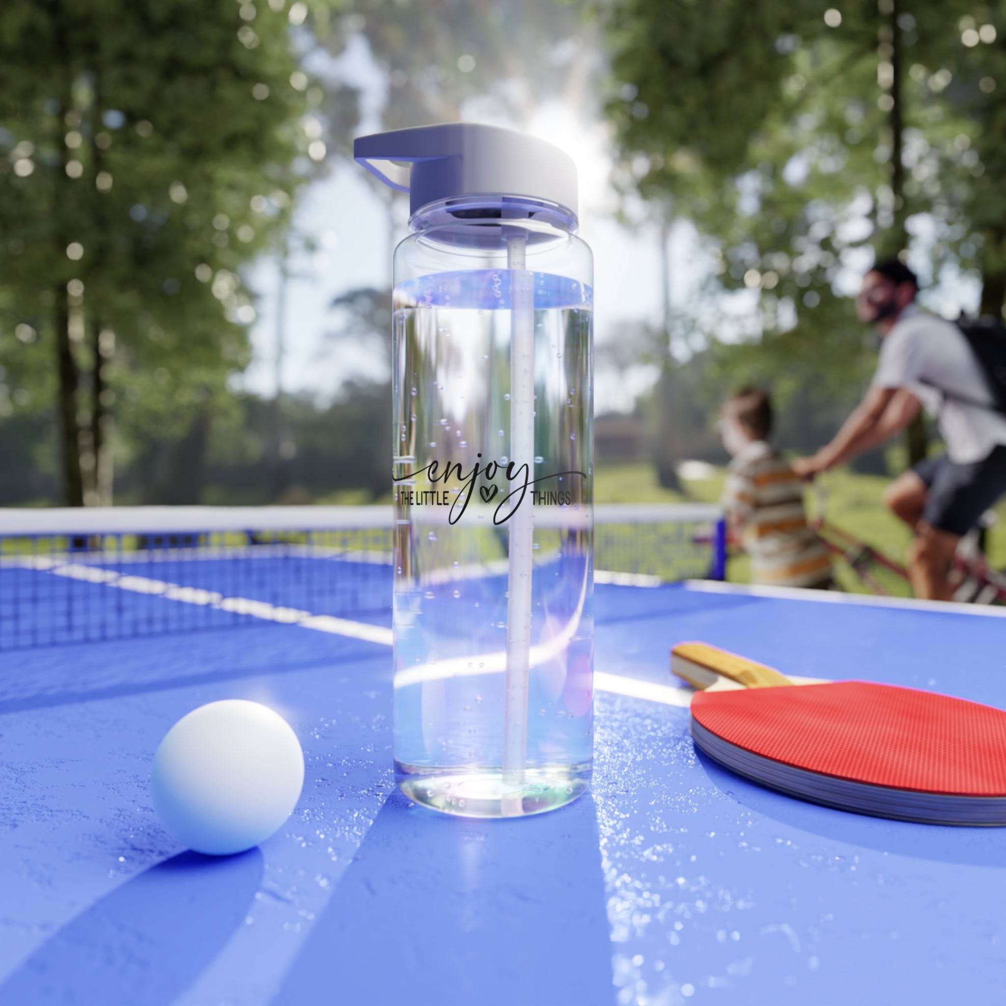 Clear BPA-free Tritan bottle with flip-top lid on blue ping pong table with paddle and ball