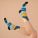 Colorful geometric print eco-friendly recycled socks by Printify worn on feet against beige background