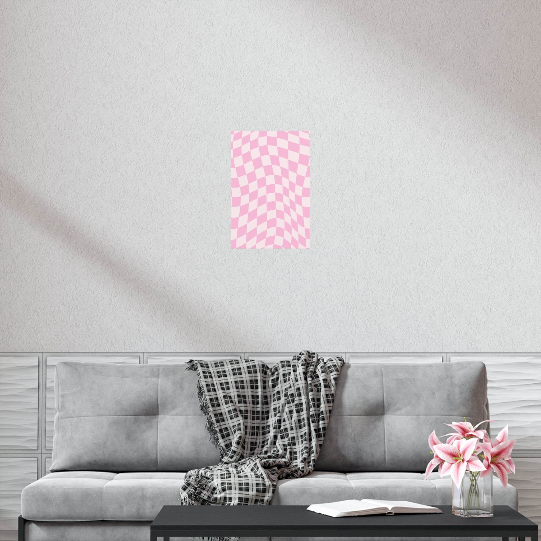 Pink checkered sustainable uncoated posters displayed on wall above gray sofa with plaid blanket in modern living room